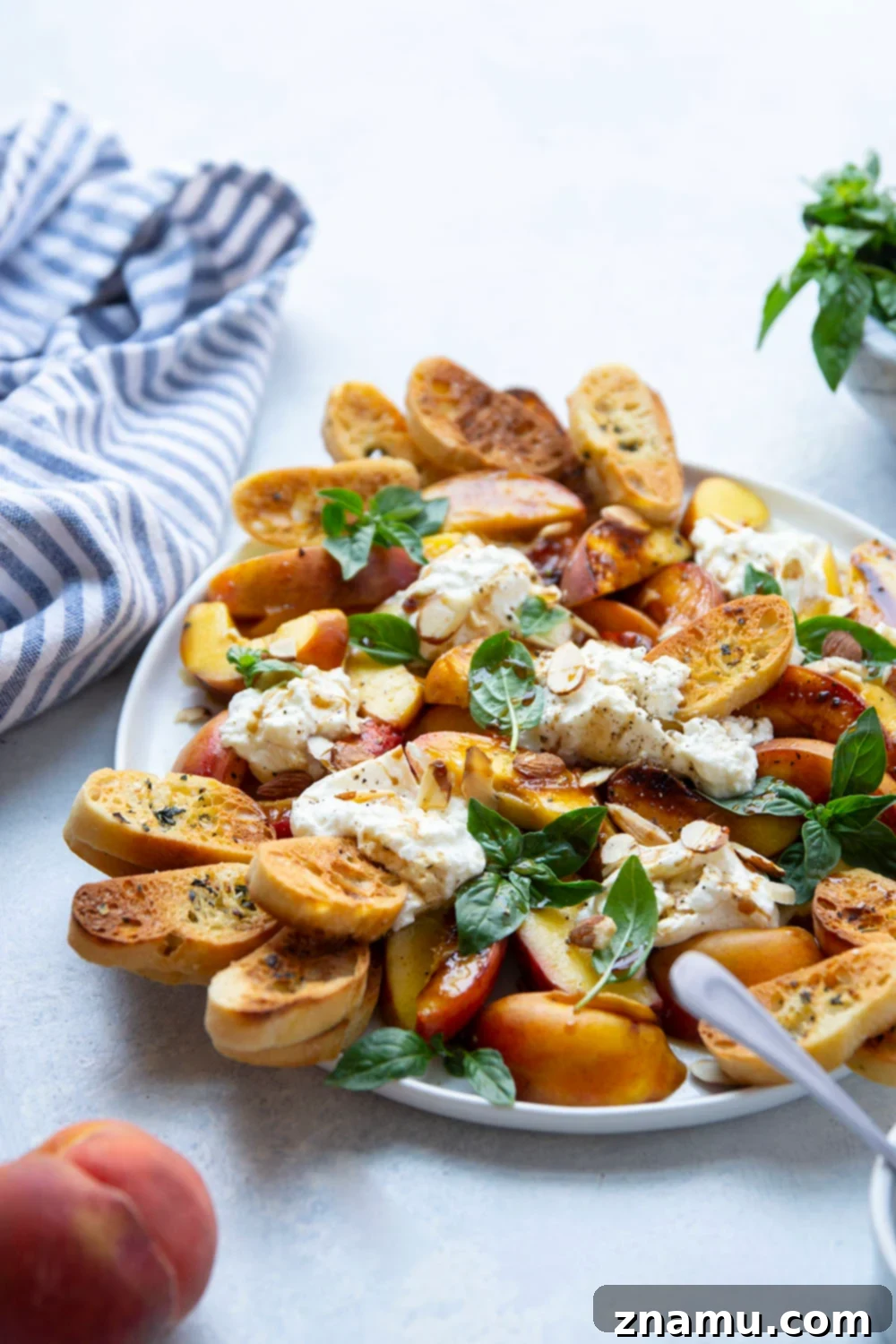 Smoky Grilled Peaches with Creamy Burrata 5 Halved peaches ready for grilling, alongside a bowl of burrata cheese and fresh basil.