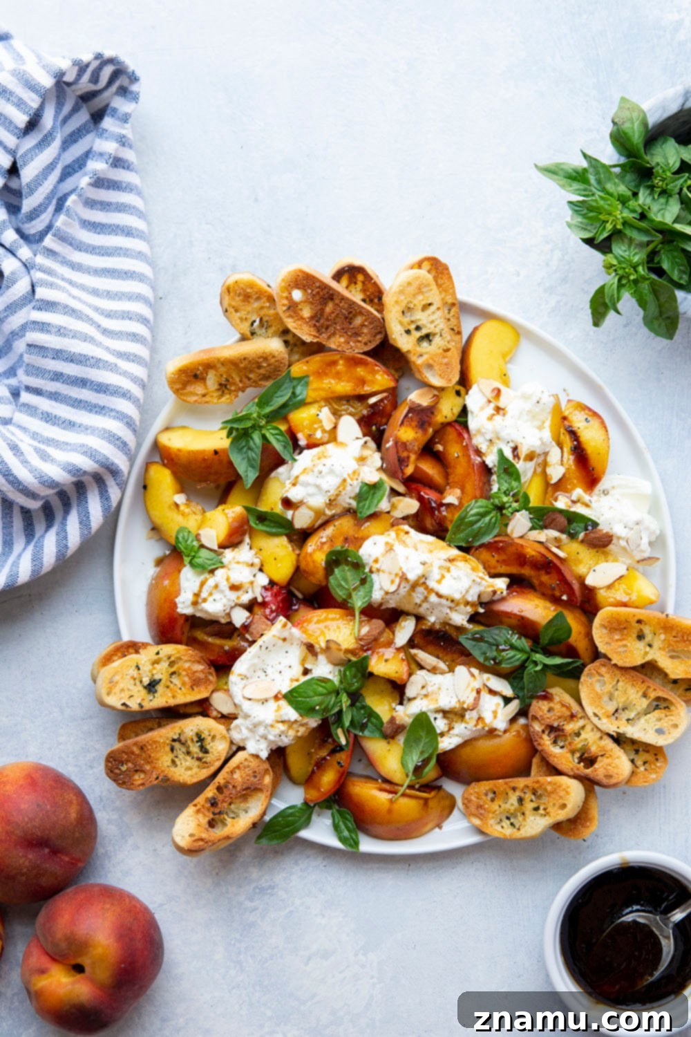 Smoky Grilled Peaches with Creamy Burrata 6 A beautifully presented platter of grilled peaches and burrata, garnished with fresh basil leaves.