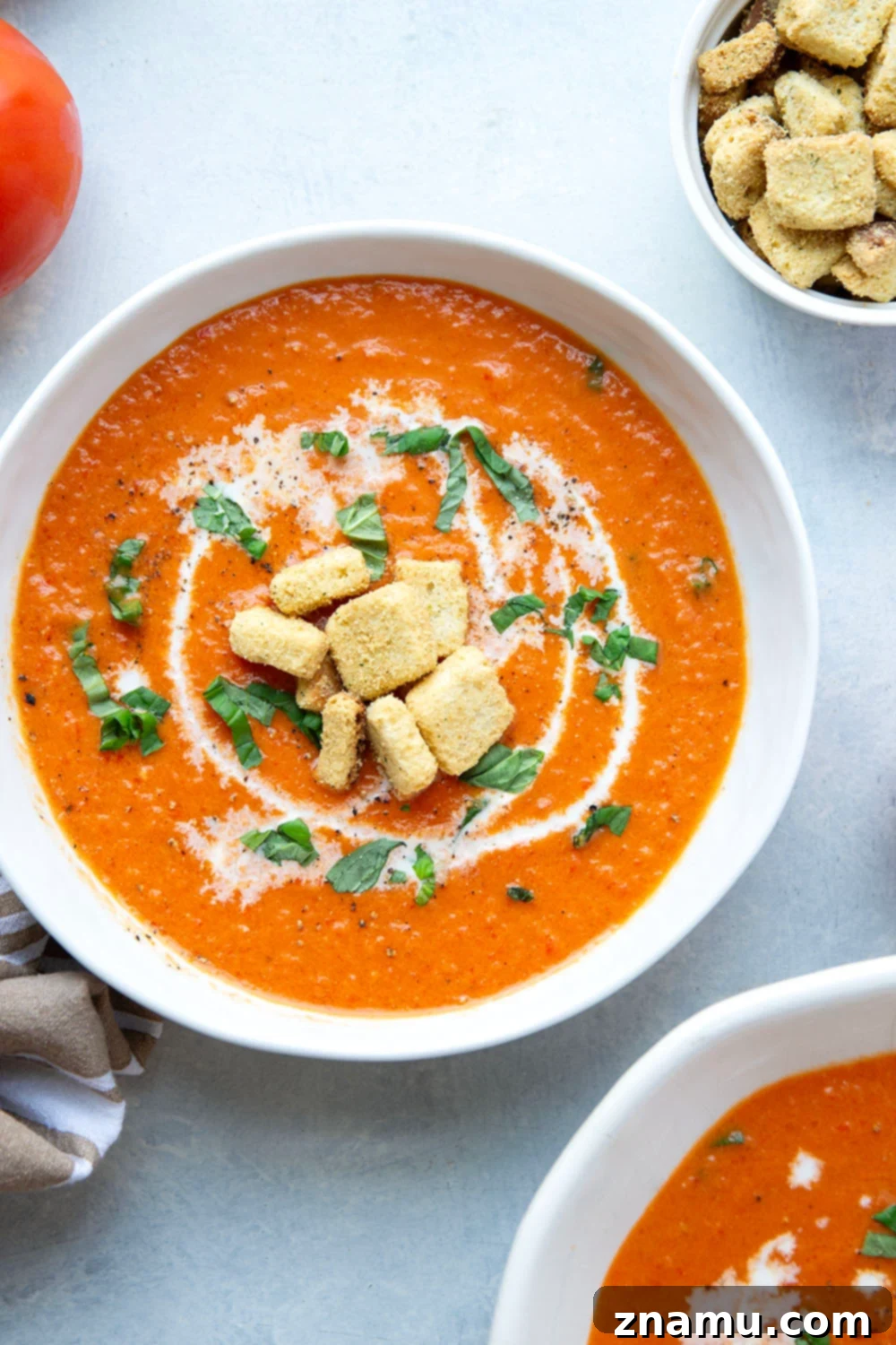 Crimson Fire-Roasted Tomato & Pepper Bisque 2 A vibrant bowl of creamy roasted red pepper tomato soup garnished with fresh basil, showcasing its rich texture and appetizing color.