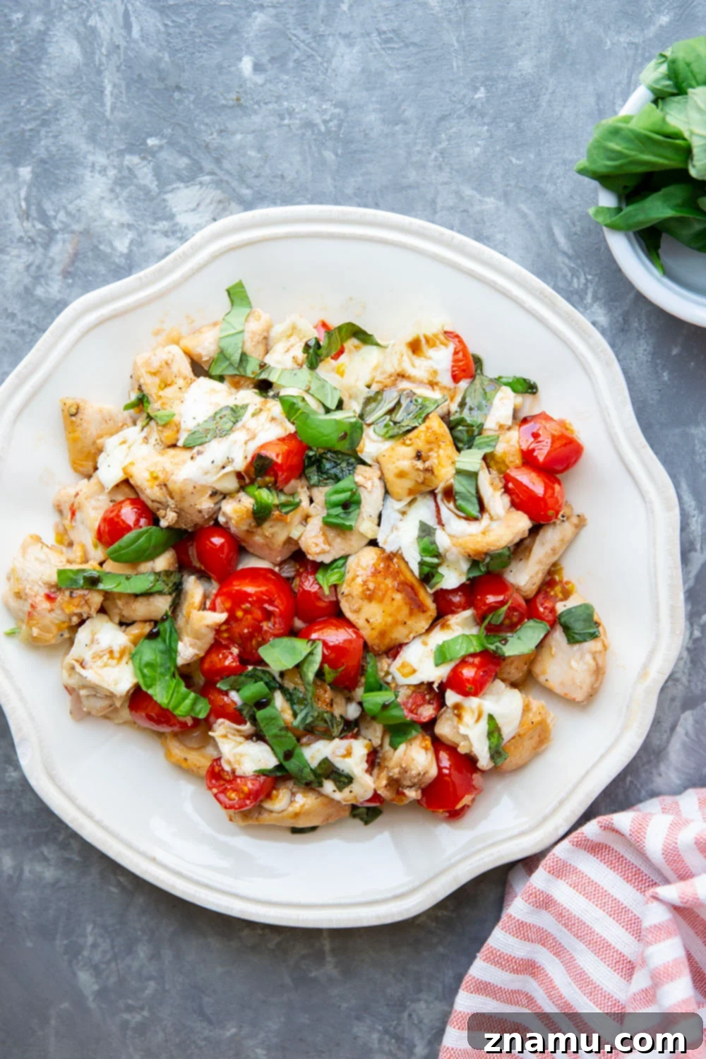 Caprese Chicken Skillet 3 An overhead shot of Skillet Caprese Chicken Bites, highlighting the rich colors of the ingredients: succulent chicken pieces, glistening cherry tomatoes, and soft mozzarella pearls, generously topped with fresh basil, ready to be served.