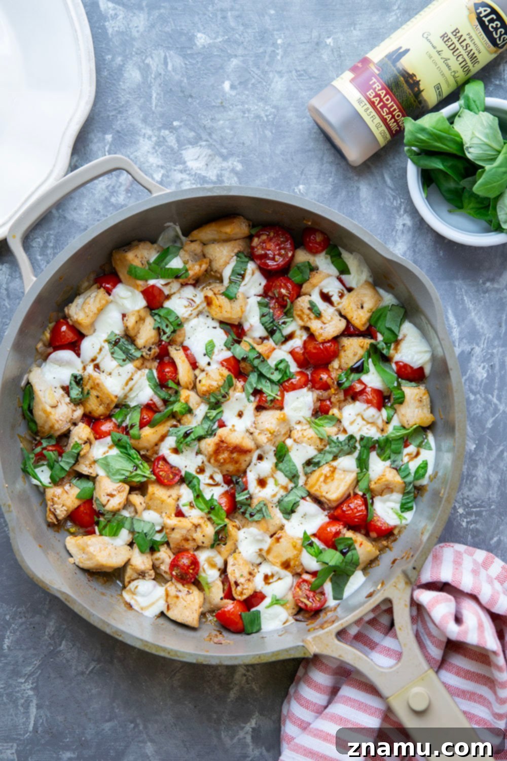 Caprese Chicken Skillet 4 A close-up of a serving of Skillet Caprese Chicken Bites, beautifully plated with rich balsamic glaze drizzled over the melted mozzarella and fresh basil leaves, ready to be enjoyed.