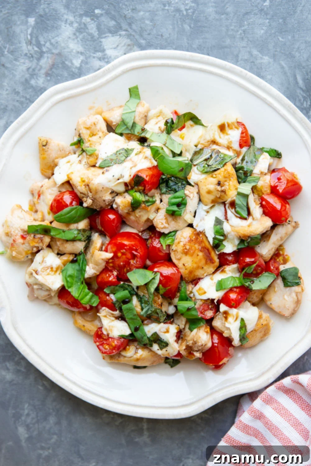 Caprese Chicken Skillet 6 A vibrant close-up of the Skillet Caprese Chicken Bites directly in the pan, showcasing the melted mozzarella stretching over the chicken and tomatoes, with rich balsamic drizzle and fresh basil, inviting immediate enjoyment.