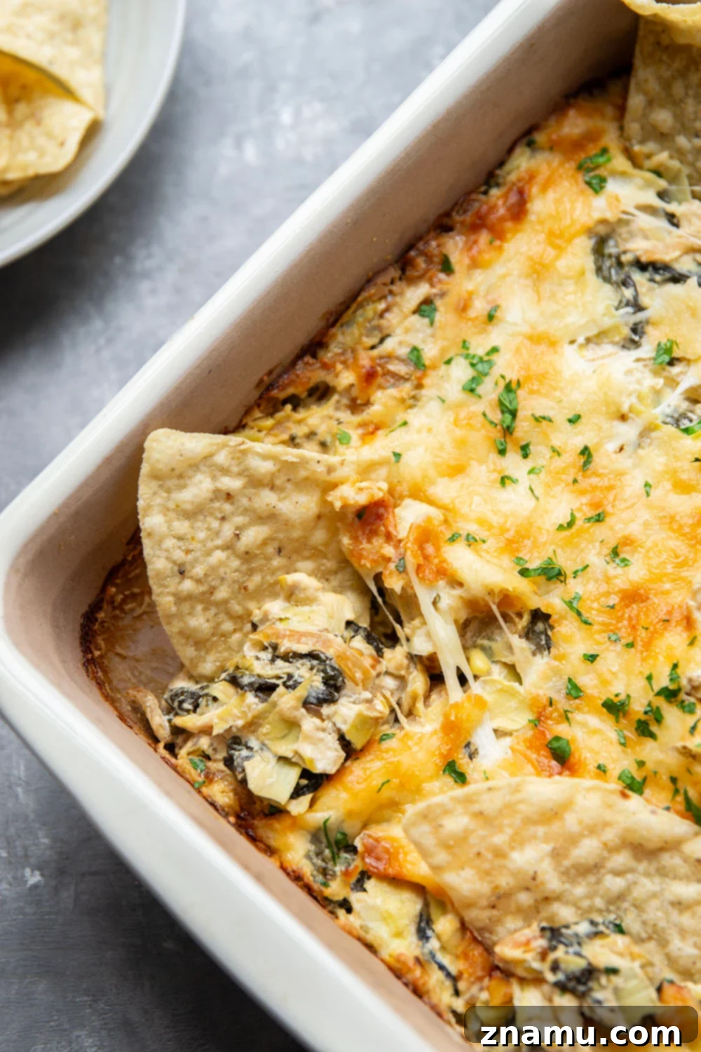 Sweet Caramelized Onion & Spinach Artichoke Bake 3 A spoonful of creamy spinach artichoke dip, showing the caramelized onion texture.