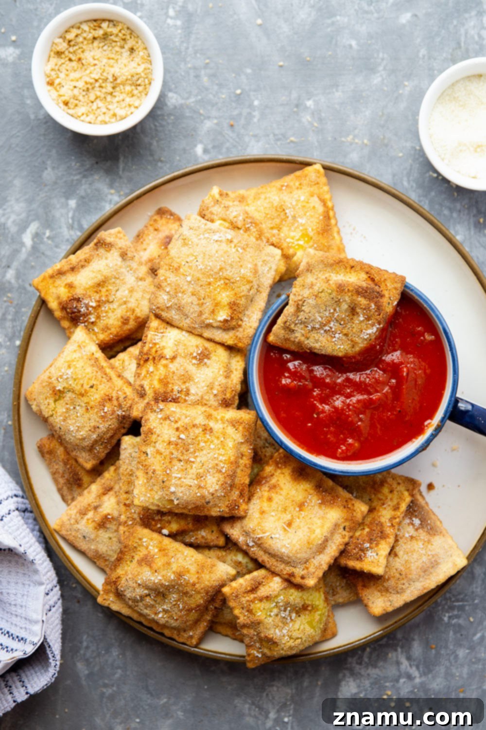 Crispy Air Fryer Ravioli 2 Crispy Air Fryer Toasted Ravioli served with marinara sauce in a bowl, garnished with fresh parsley.
