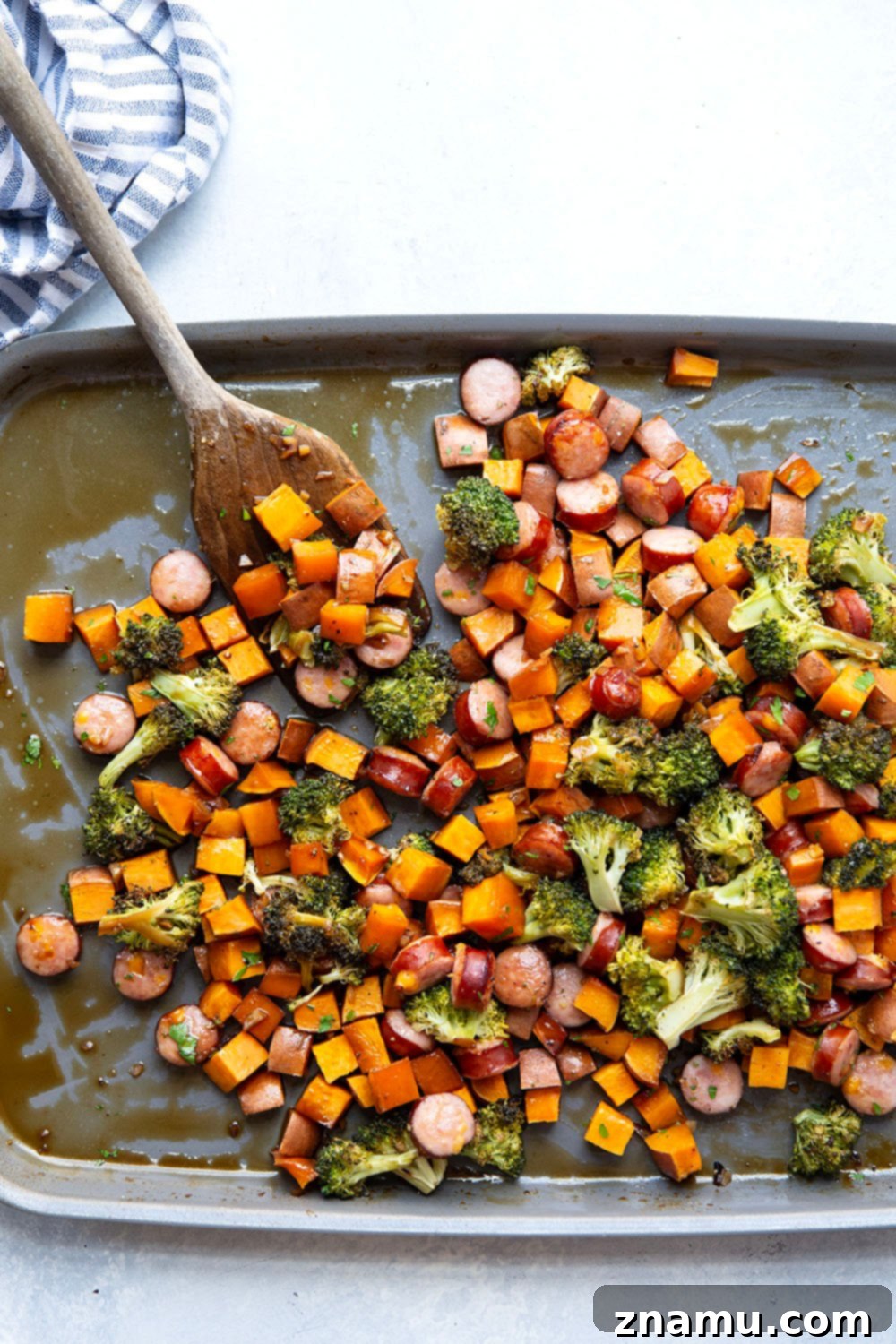 Sticky Honey Garlic Sheet Pan Sausage and Sweet Potatoes 3 Close-up of roasted sausage, sweet potatoes, and broccoli glazed with honey garlic sauce on a sheet pan, showcasing textures and colors.