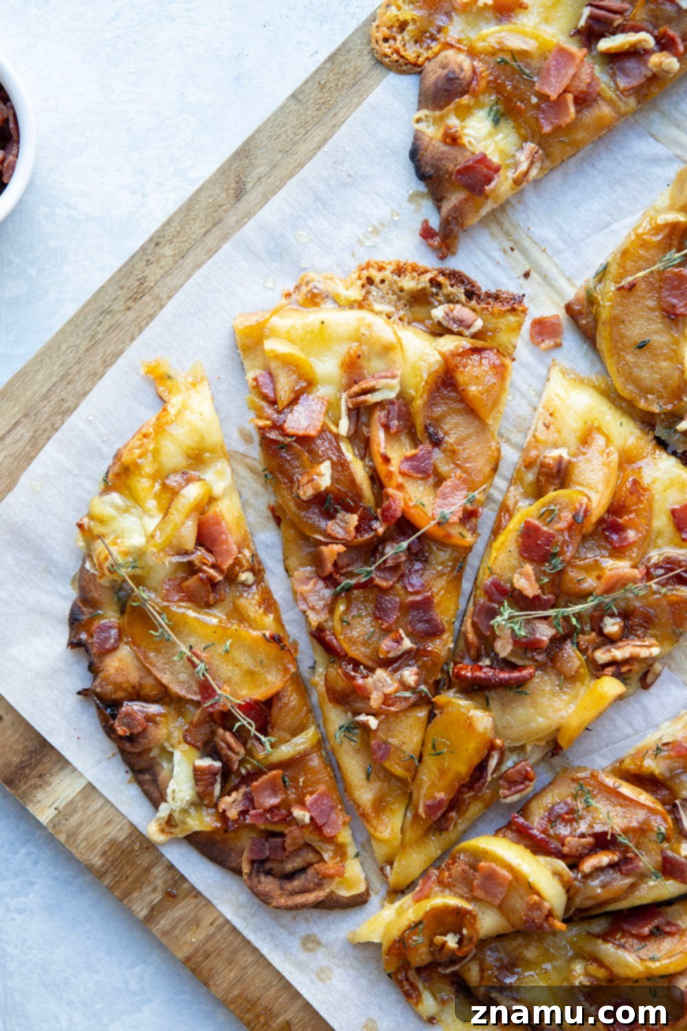 Gourmet Caramelized Apple Brie Flatbread 2 A close-up view of a beautifully prepared caramelized apple brie flatbread, showcasing golden apples, melted brie, and crispy bacon.