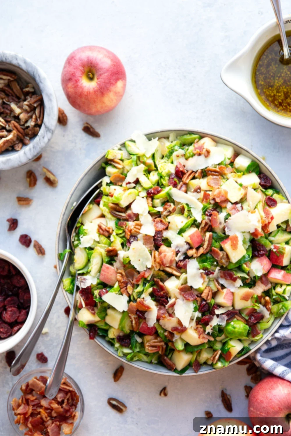 A close-up of the warm Brussels sprouts salad, showing the finely shredded and sautéed Brussels sprouts, diced apples, and crispy bacon, before being fully dressed.