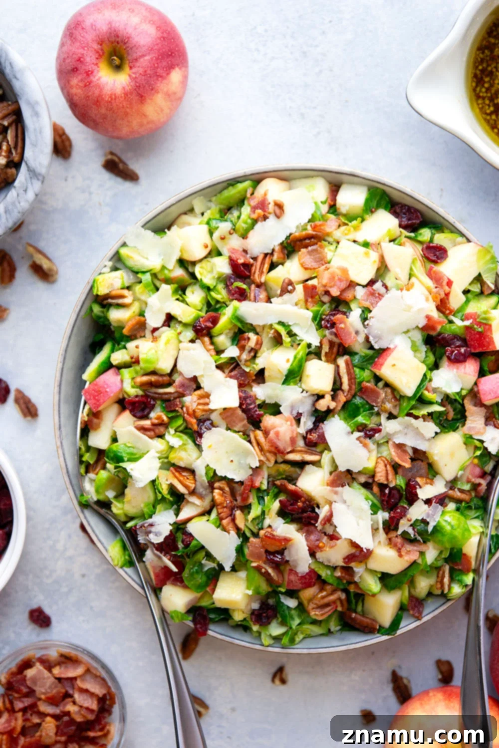 A large serving bowl filled with the warm Brussels sprouts salad, freshly tossed and garnished with shaved Parmesan, ready to be served.
