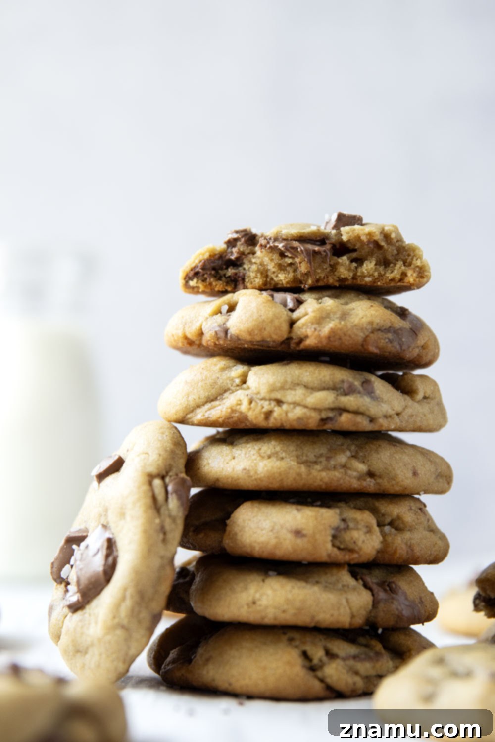 Decadent Brown Butter Chocolate Chunk Cookies 6 A hand reaching for a warm brown butter chocolate chunk cookie, steam gently rising.