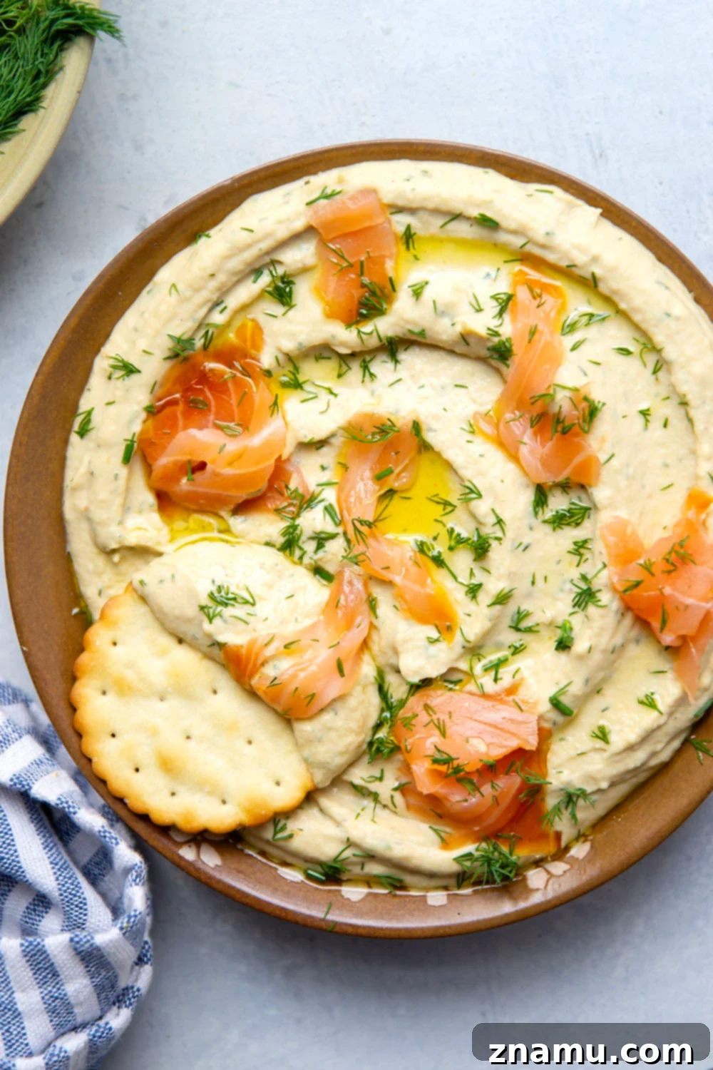 Close-up of freshly prepared Dill Smoked Salmon Hummus garnished with extra dill and a strip of salmon, ready to be served.