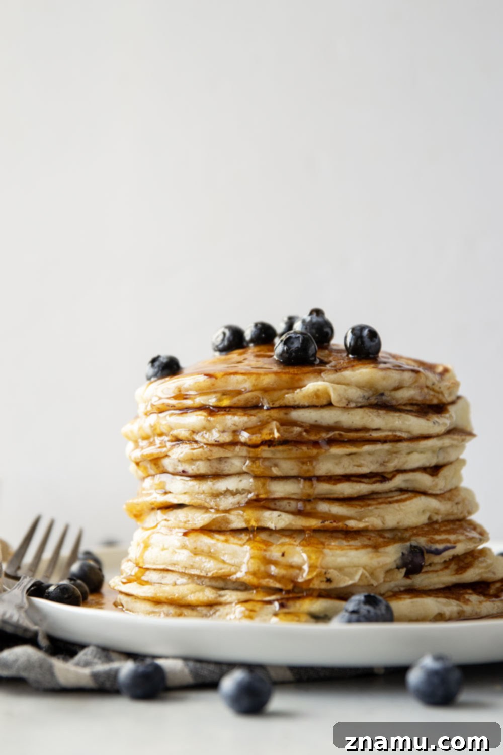 Pillowy Blueberry Ricotta Pancakes 6 Stacked blueberry ricotta pancakes drizzled with maple syrup and fresh berries