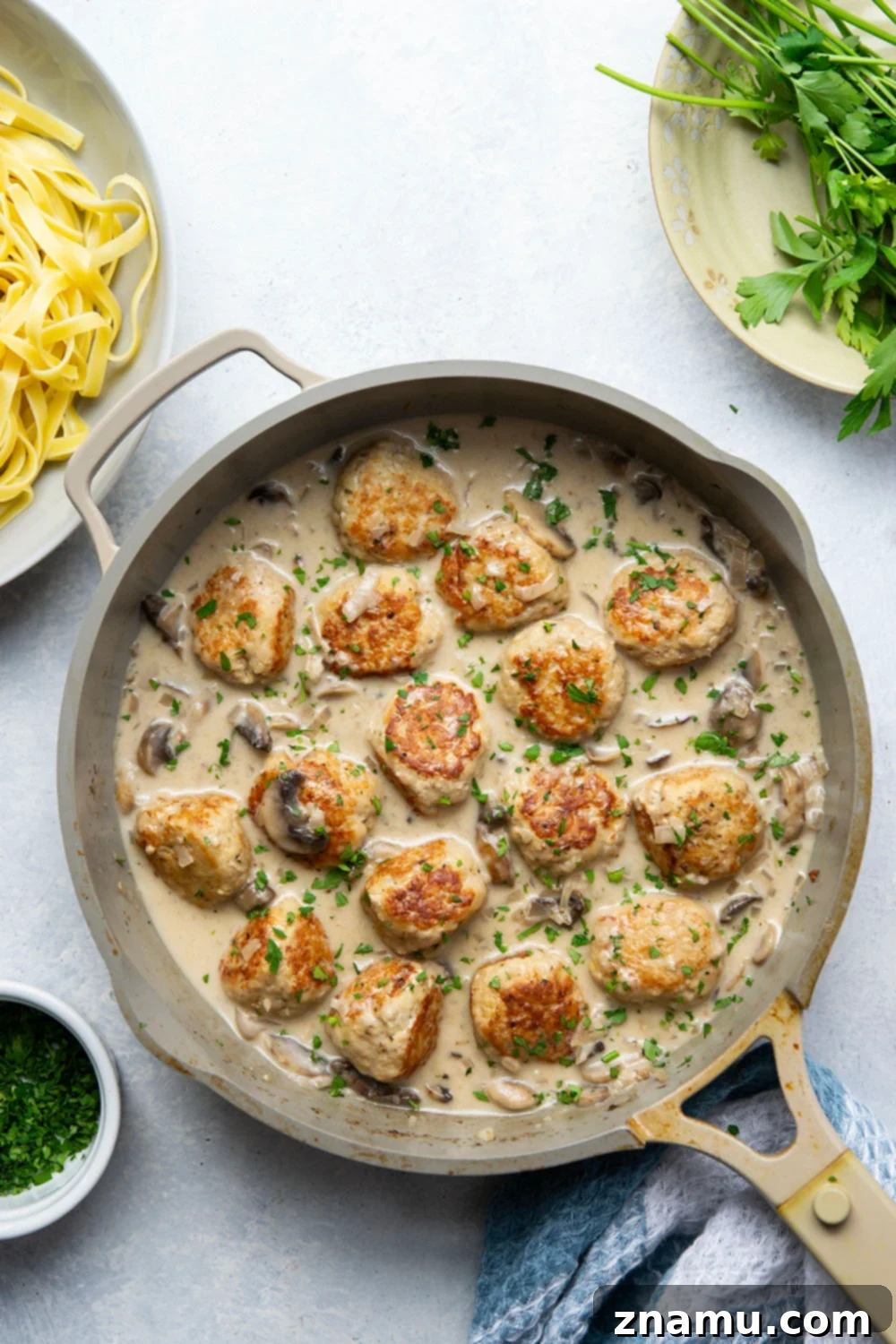 Flavorful Chicken Marsala Meatballs 2 Close-up of golden-brown chicken marsala meatballs in a creamy mushroom sauce, served with fettuccine pasta.