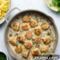 Flavorful Chicken Marsala Meatballs 8 Close-up of golden-brown chicken marsala meatballs in a creamy mushroom sauce, served with fettuccine pasta.