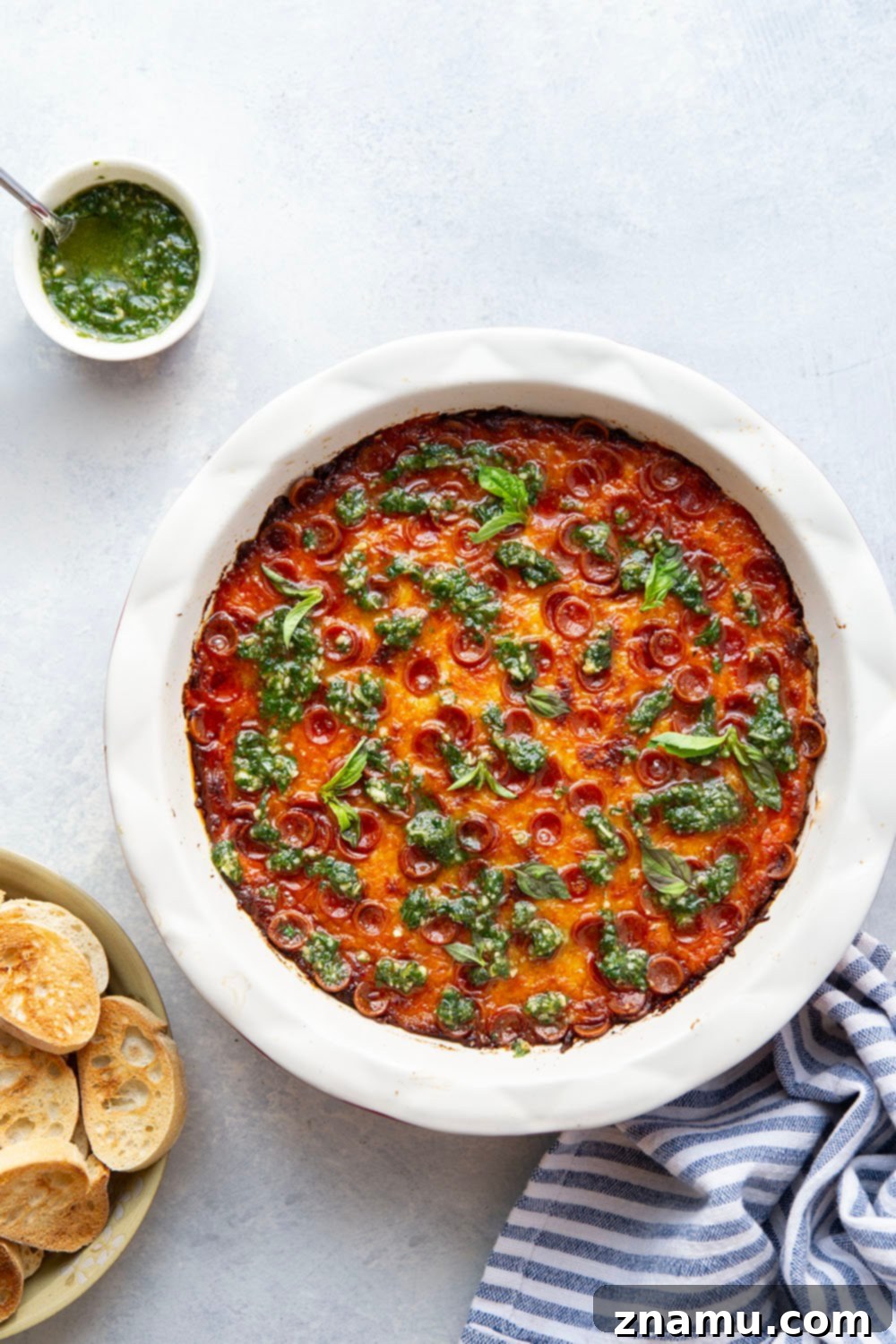 Gooey Baked Pesto Pizza Dip 3 This baked pizza dip features layers of gooey cheese, pizza sauce, mini pepperoni, and drizzles of fresh pesto on top. Serve this crowd-pleasing dip with lots of toasted bread for dipping.