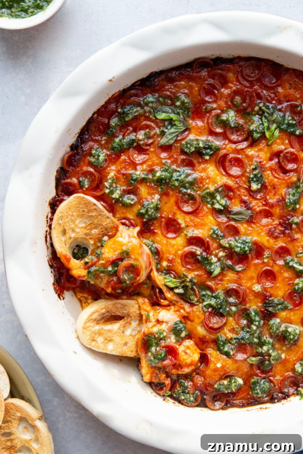 Gooey Baked Pesto Pizza Dip 4 This baked pizza dip features layers of gooey cheese, pizza sauce, mini pepperoni, and drizzles of fresh pesto on top. Serve this crowd-pleasing dip with lots of toasted bread for dipping.