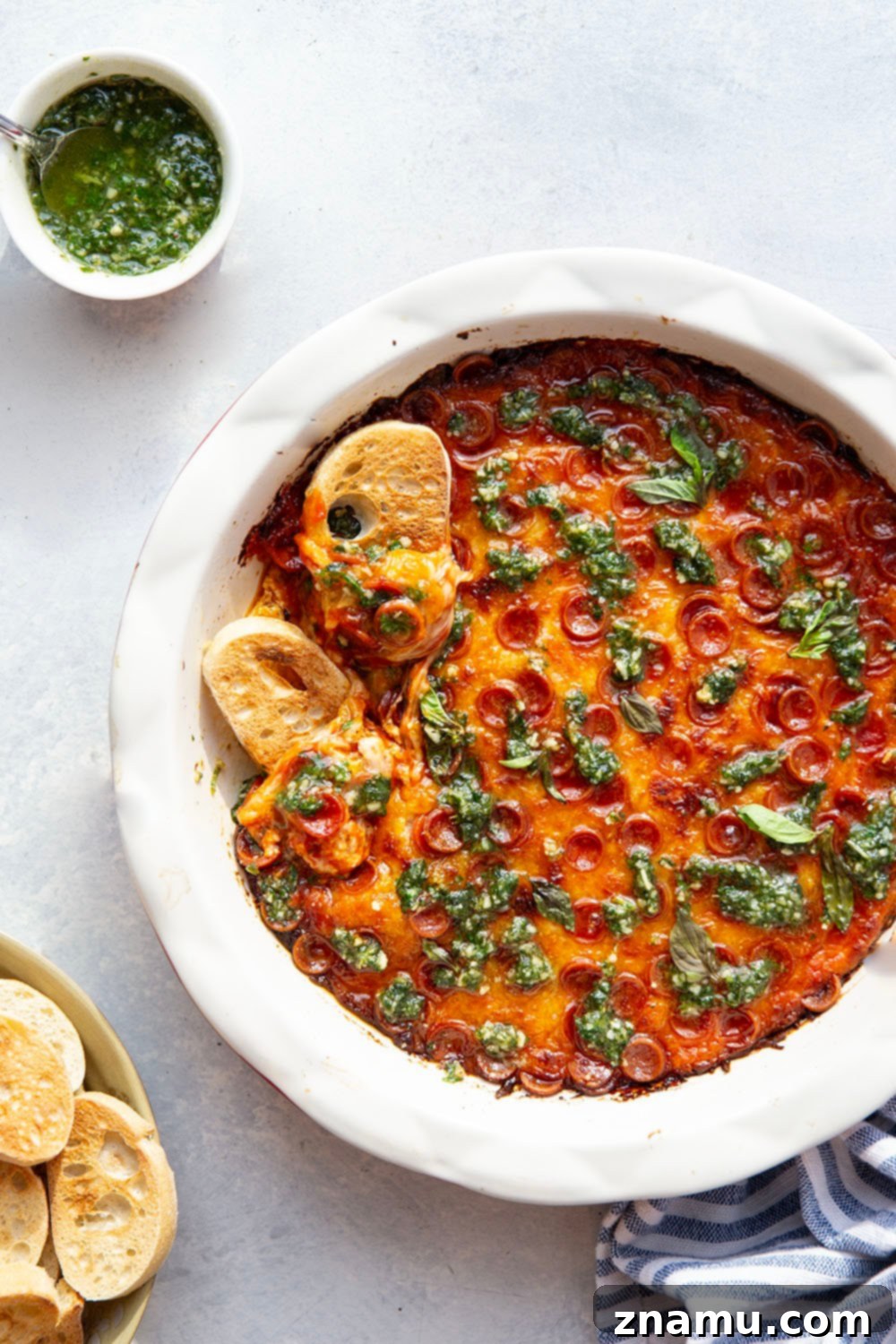 Gooey Baked Pesto Pizza Dip 5 This baked pizza dip features layers of gooey cheese, pizza sauce, mini pepperoni, and drizzles of fresh pesto on top. Serve this crowd-pleasing dip with lots of toasted bread for dipping.