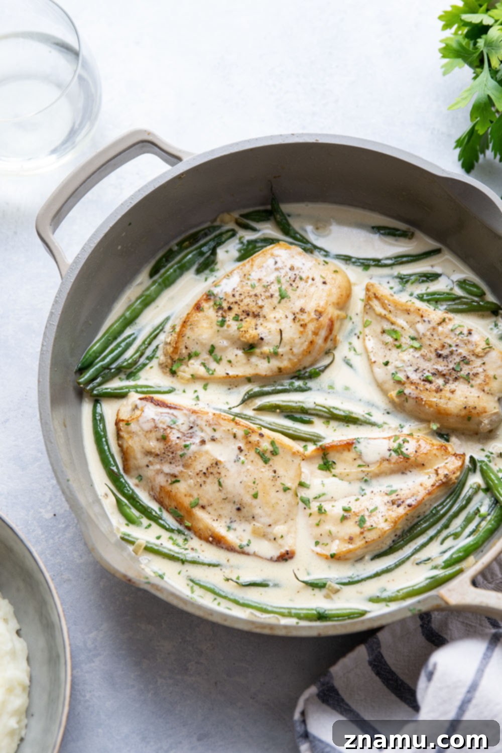 Velvety White Wine Chicken 5 Seared chicken breasts and green beans cooking in a skillet with creamy white wine sauce.