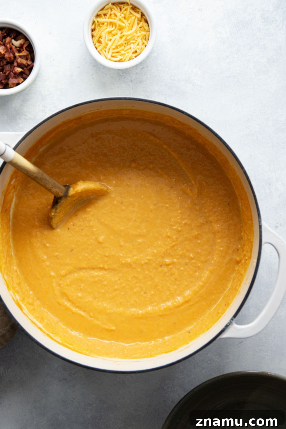 Ultimate Baked Sweet Potato Soup 3 Close-up of the rich, orange color and creamy texture of Loaded Baked Sweet Potato Soup, topped with melted cheese and fresh green onions.
