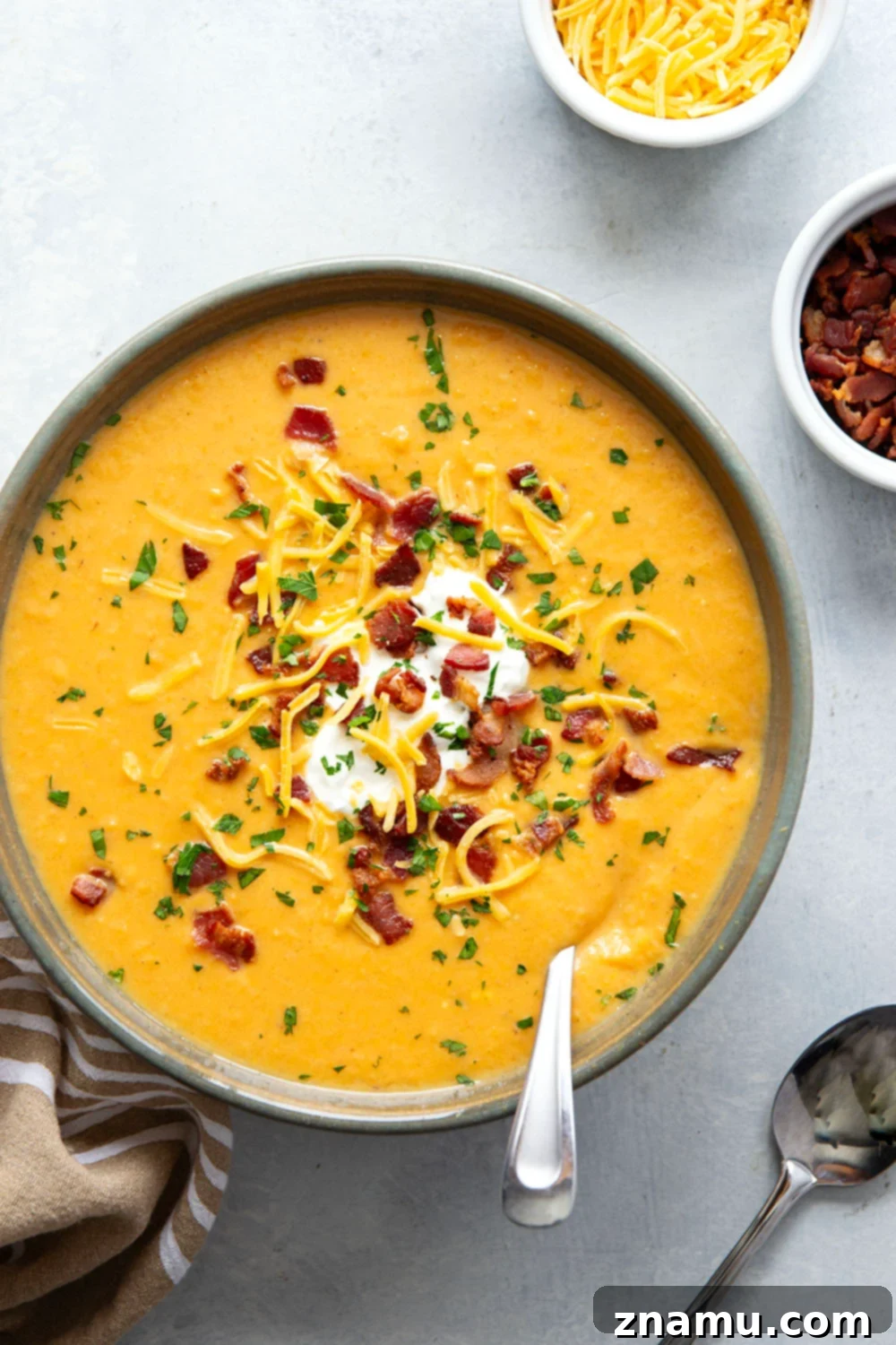 Ultimate Baked Sweet Potato Soup 4 A generous serving of Loaded Baked Sweet Potato Soup in a rustic bowl, garnished with a sprinkle of crispy bacon and finely chopped herbs.