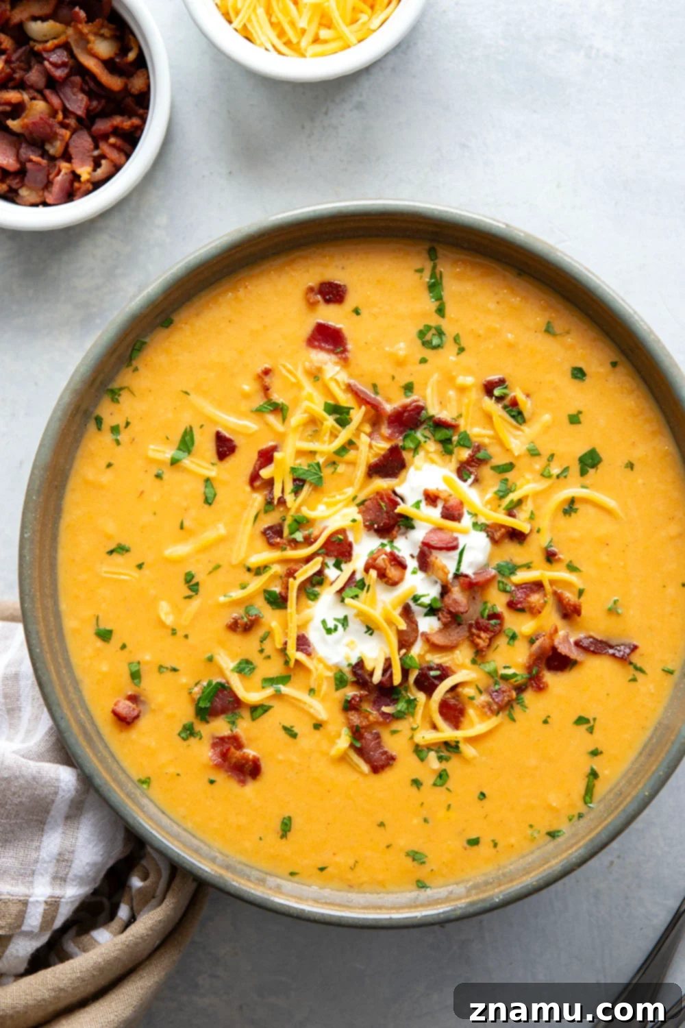 Ultimate Baked Sweet Potato Soup 6 A vibrant and comforting bowl of Loaded Baked Sweet Potato Soup, garnished with crispy bacon and fresh chives, captured from an overhead view.