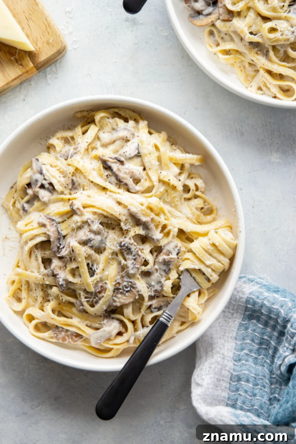 Velvety Asiago Shiitake Alfredo Fettuccine 6 A bowl of hot Asiago Shiitake Mushroom Fettuccine Alfredo topped with fresh parsley and black pepper.