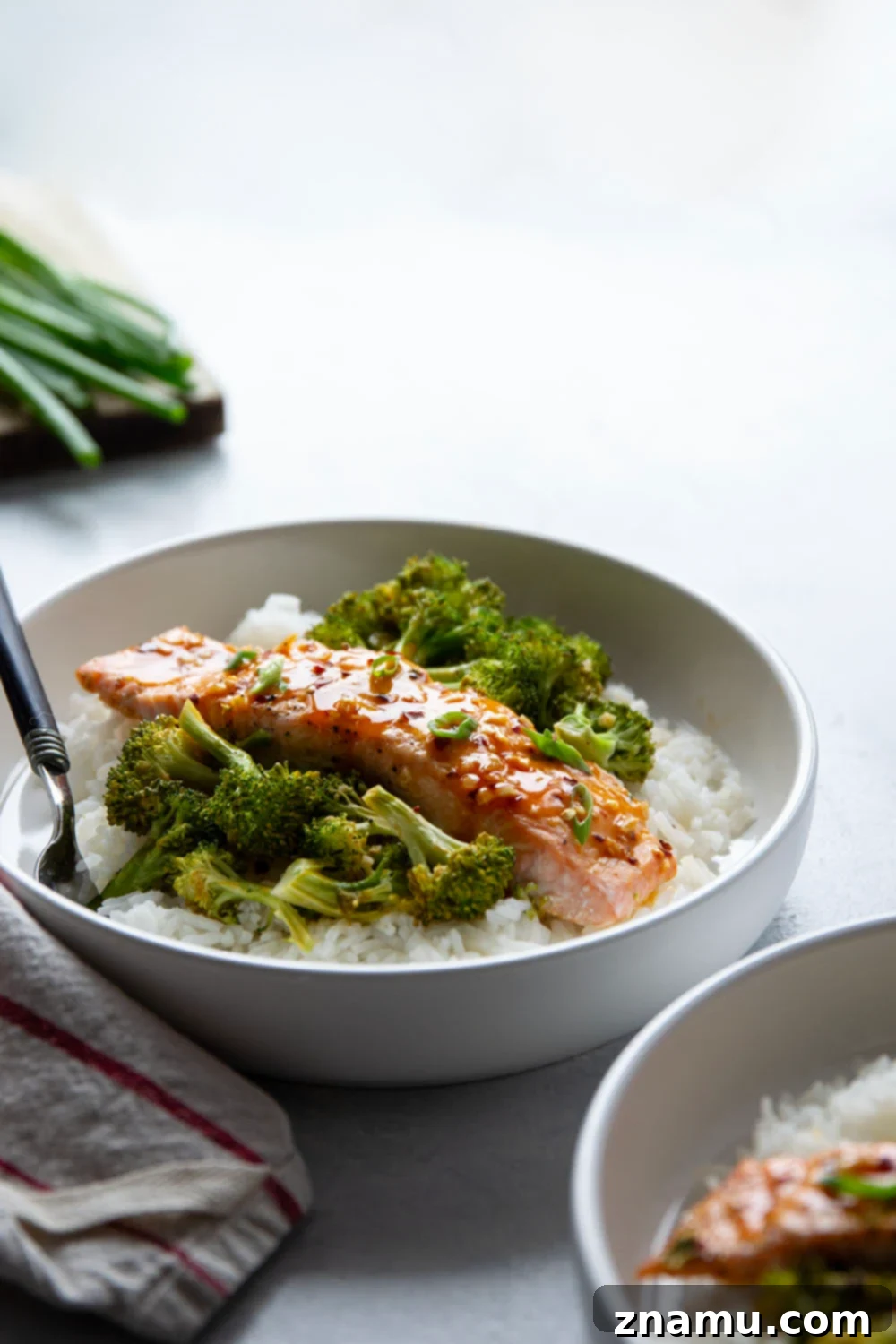 Spicy Honey Glazed Salmon with Roasted Broccoli 6 A vibrant, close-up shot of Hot Honey Glazed Salmon and roasted broccoli served on a plate with steamed rice and garnished with fresh green onions, highlighting the irresistible glaze and perfect texture.