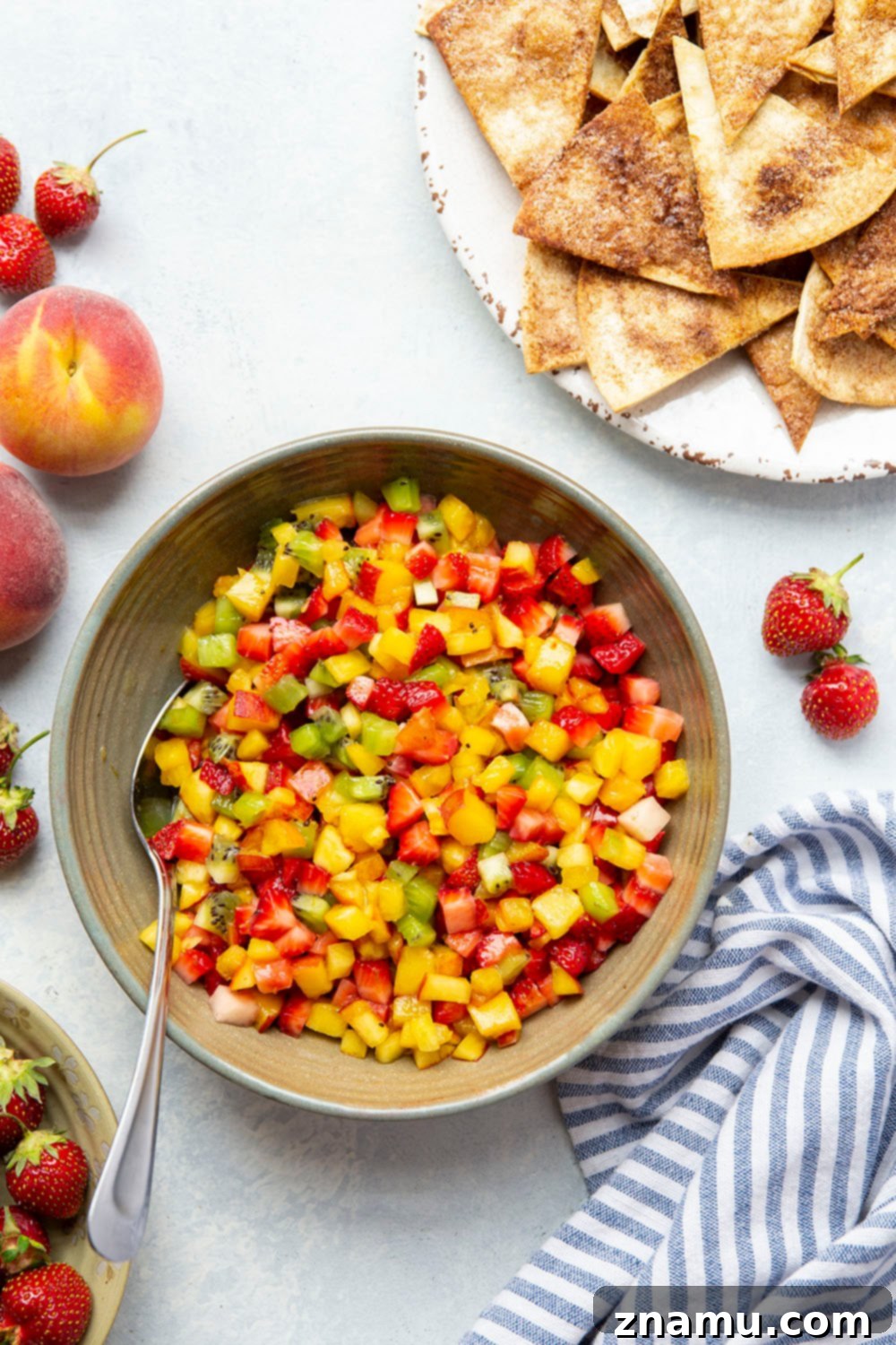 Cinnamon Sugar Crisps with Fresh Fruit Dip 5 Hand scooping fresh fruit salsa with a homemade cinnamon chip.