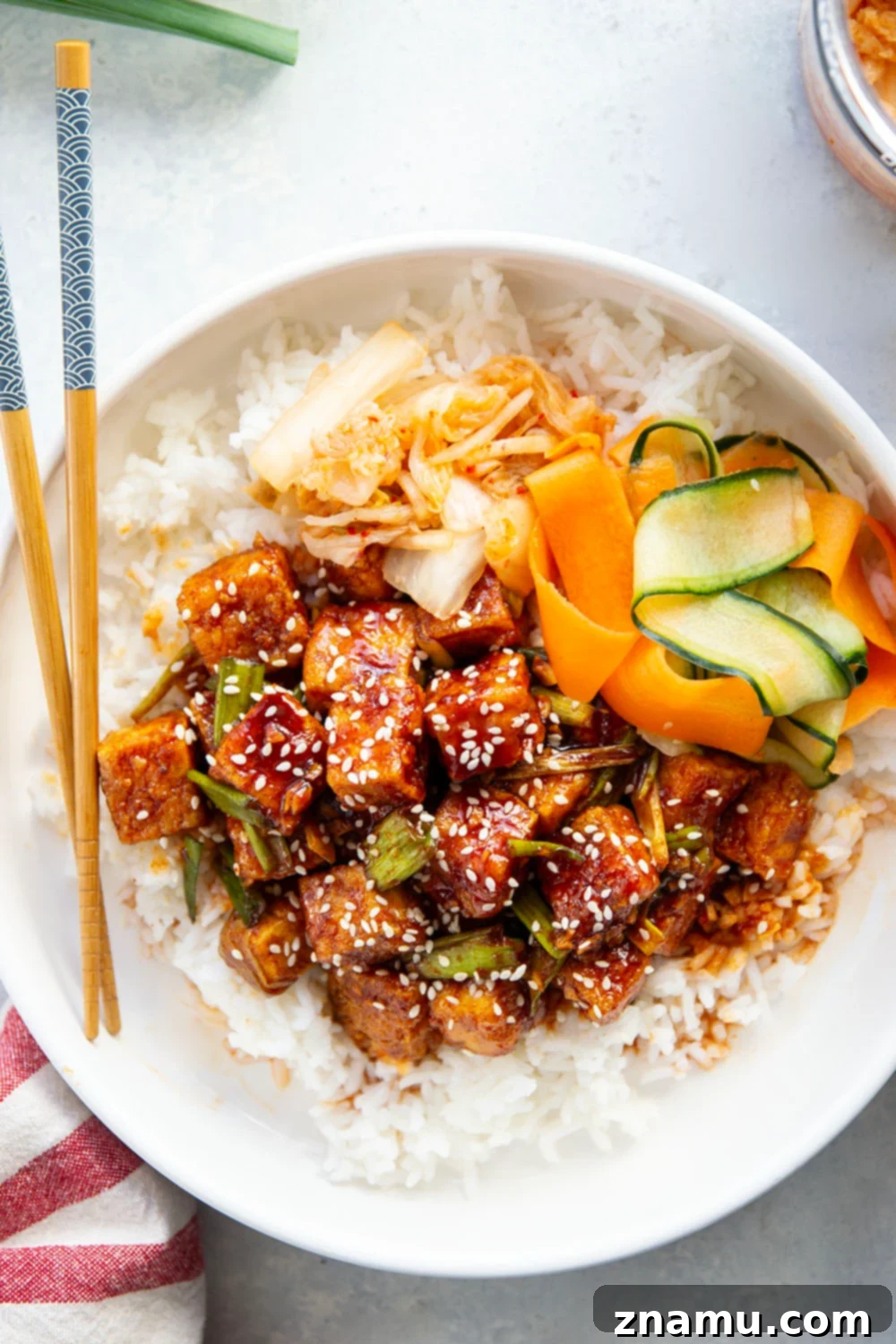 A beautifully arranged gochujang tofu bowl with rice, pickled vegetables, and kimchi, ready to be enjoyed. Highlighted as a great meal prep option.