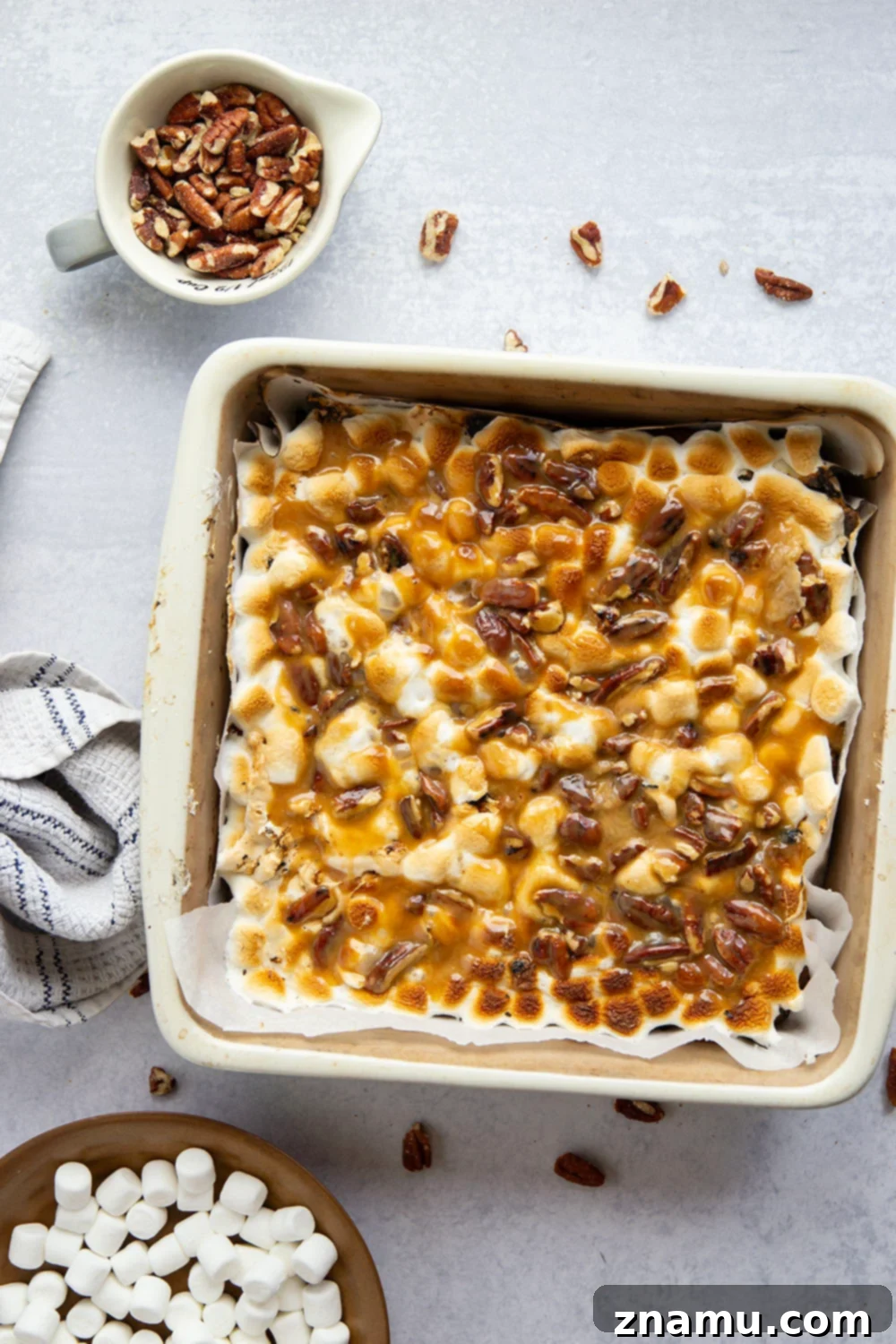 A close-up shot of a single square of luscious caramel pecan brownie, showcasing the melted marshmallow and rich caramel sauce.