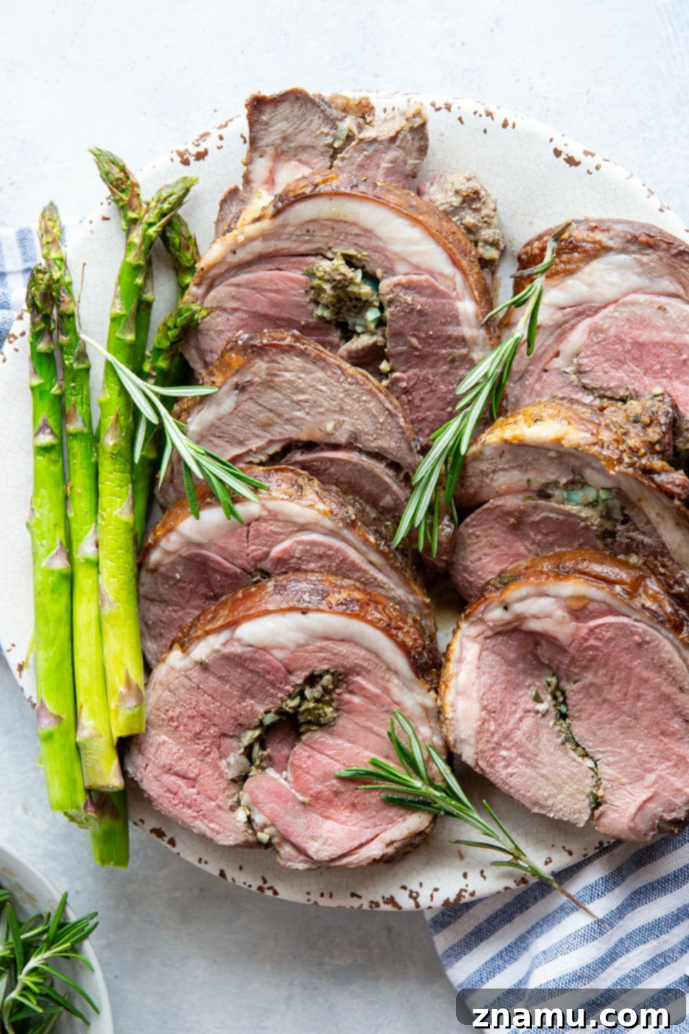 Aromatic Rosemary Garlic Leg of Lamb 5 A beautifully roasted rosemary garlic leg of lamb, sliced to reveal juicy meat and herb stuffing.