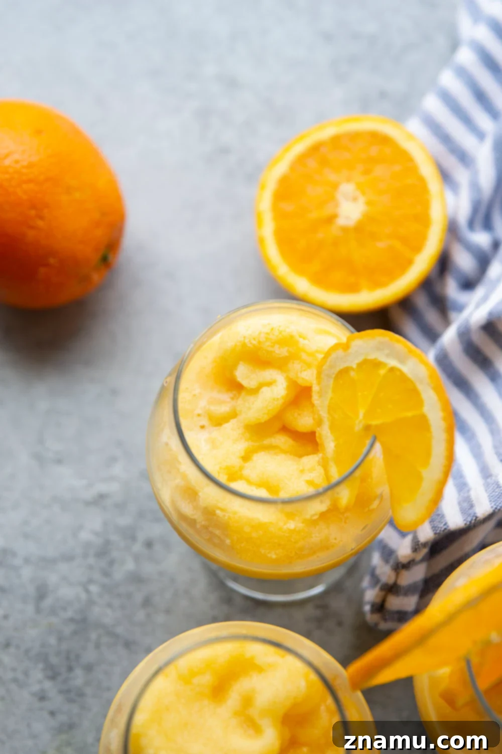 Orange Julius Frosted Delights 6 Two glasses of Orange Julius Slushies with straws and orange slices.