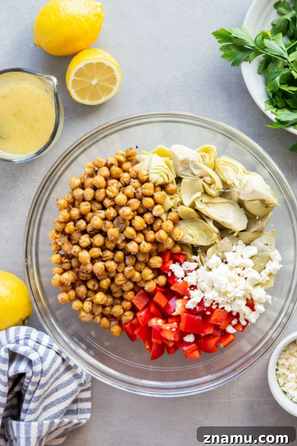 Zesty Artichoke and Crispy Chickpea Medley 4 A bowl of Crispy Chickpea Artichoke Salad, showcasing the diverse ingredients including artichoke hearts, roasted chickpeas, bell peppers, and feta cheese, generously coated in a bright lemon dressing. This image highlights the freshness and hearty nature of the salad.