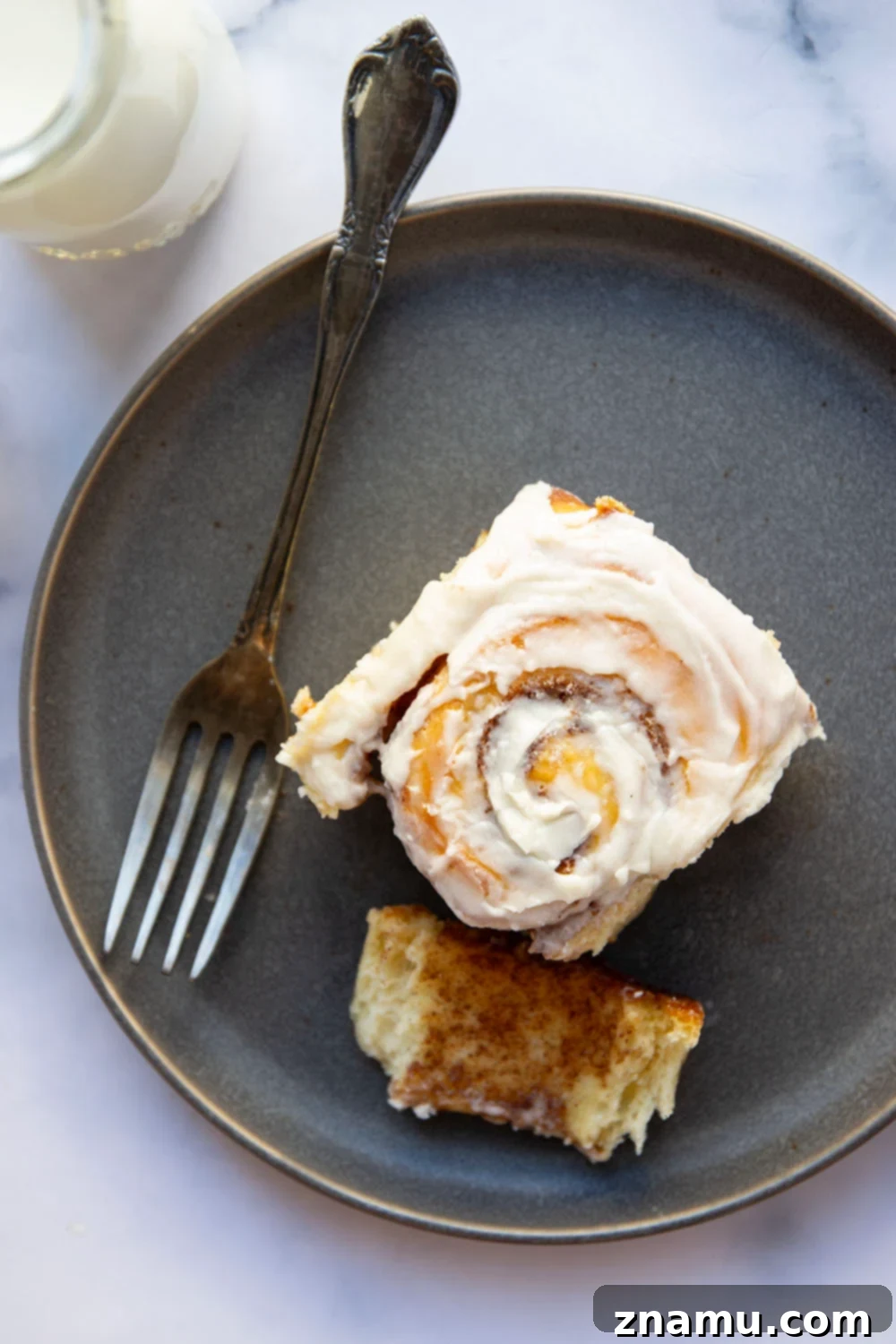Wake Up To Warm Cinnamon Rolls 6 A glorious pan of freshly baked overnight cinnamon rolls, still warm, with a smooth and thick layer of cream cheese frosting spread evenly across them, ready to be served.