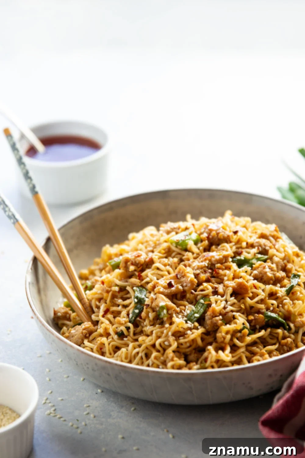 Sweet Chili Glazed Chicken Noodles 6 A large bowl of Ground Chicken Sweet Chili Noodles garnished with sesame seeds and fresh green onions, ready to be served and enjoyed.