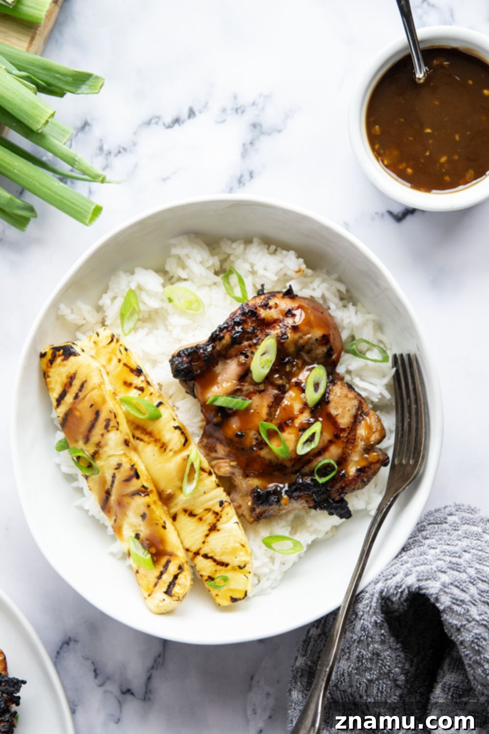 Close-up of grilled teriyaki chicken and pineapple garnished with green onions