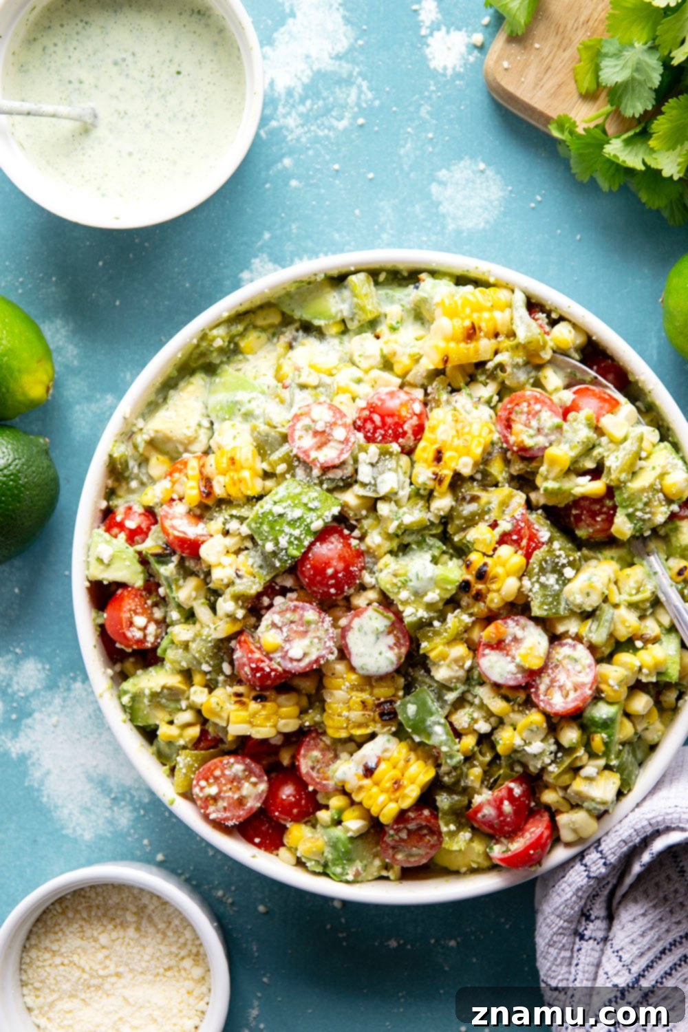 Smoky Poblano Corn Salad with Fresh Cilantro Crema 2 A close-up of Charred Poblano Corn Salad, showing vibrant corn kernels, green poblano pieces, and red cherry tomatoes mixed with a creamy dressing.