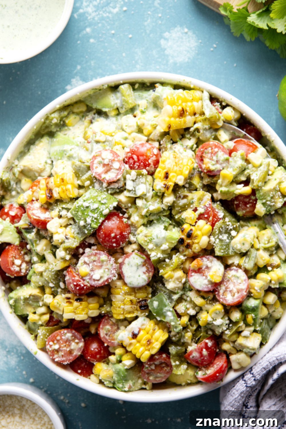 Smoky Poblano Corn Salad with Fresh Cilantro Crema 4 Close-up of a serving spoon scooping Charred Poblano Corn Salad from a bowl, showing the vibrant dressing.