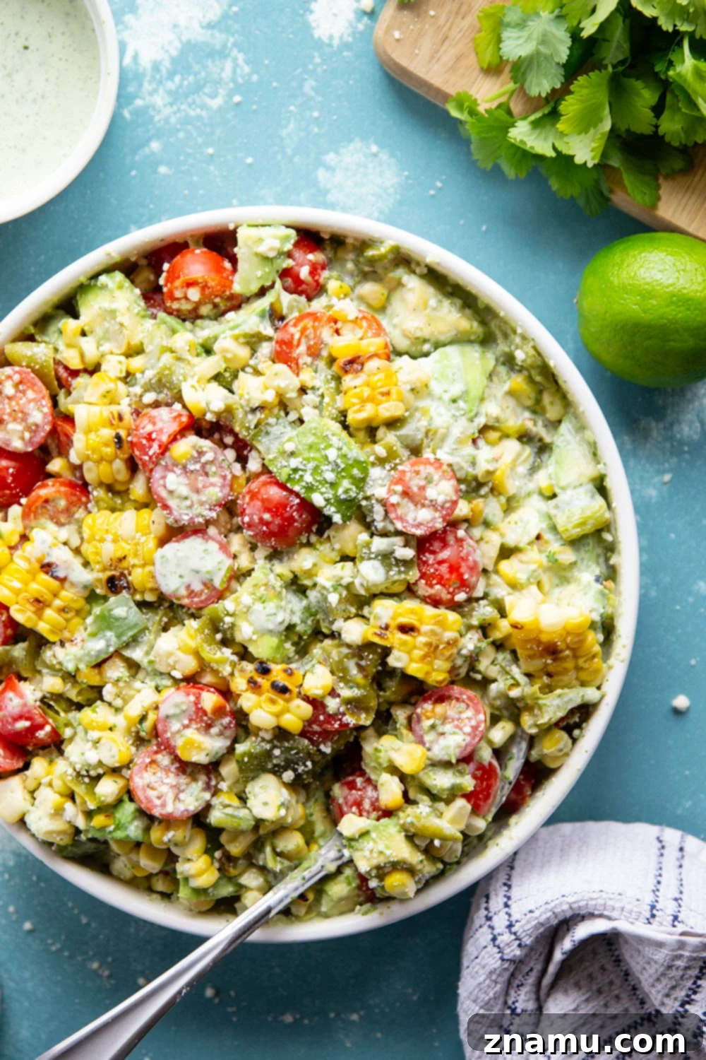 Smoky Poblano Corn Salad with Fresh Cilantro Crema 6 A vibrant bowl of Charred Poblano Corn Salad with creamy dressing visible, garnished with fresh cilantro.