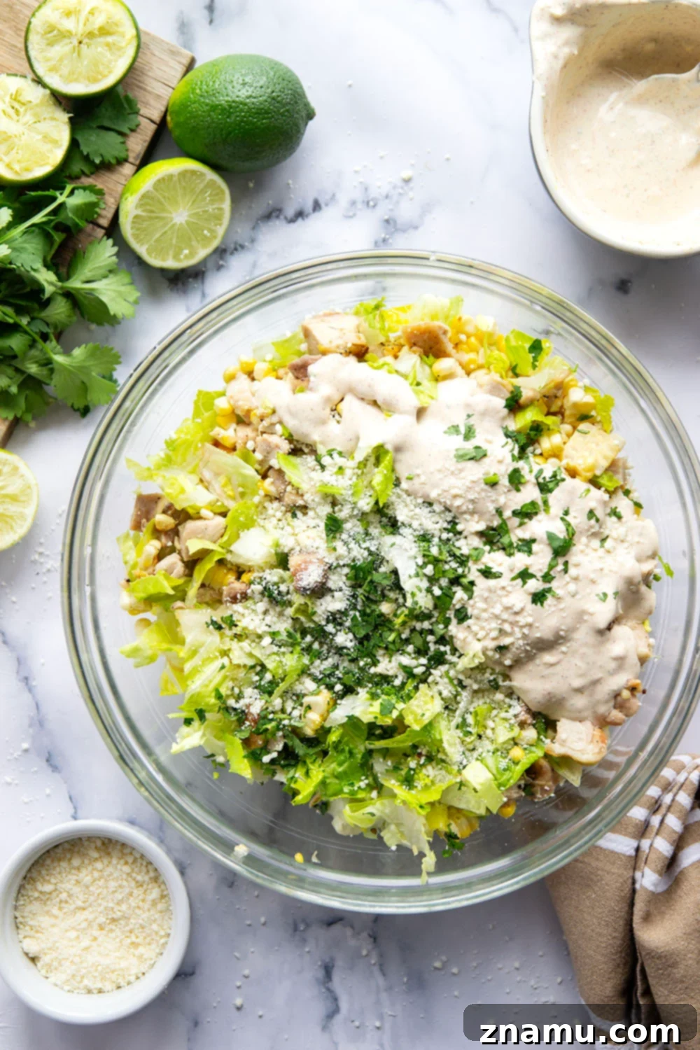Zesty Elote Chopped Salad 4 Ingredients for a Mexican Street Corn Chopped Salad laid out on a wooden board, showcasing fresh corn, chicken, and lime.