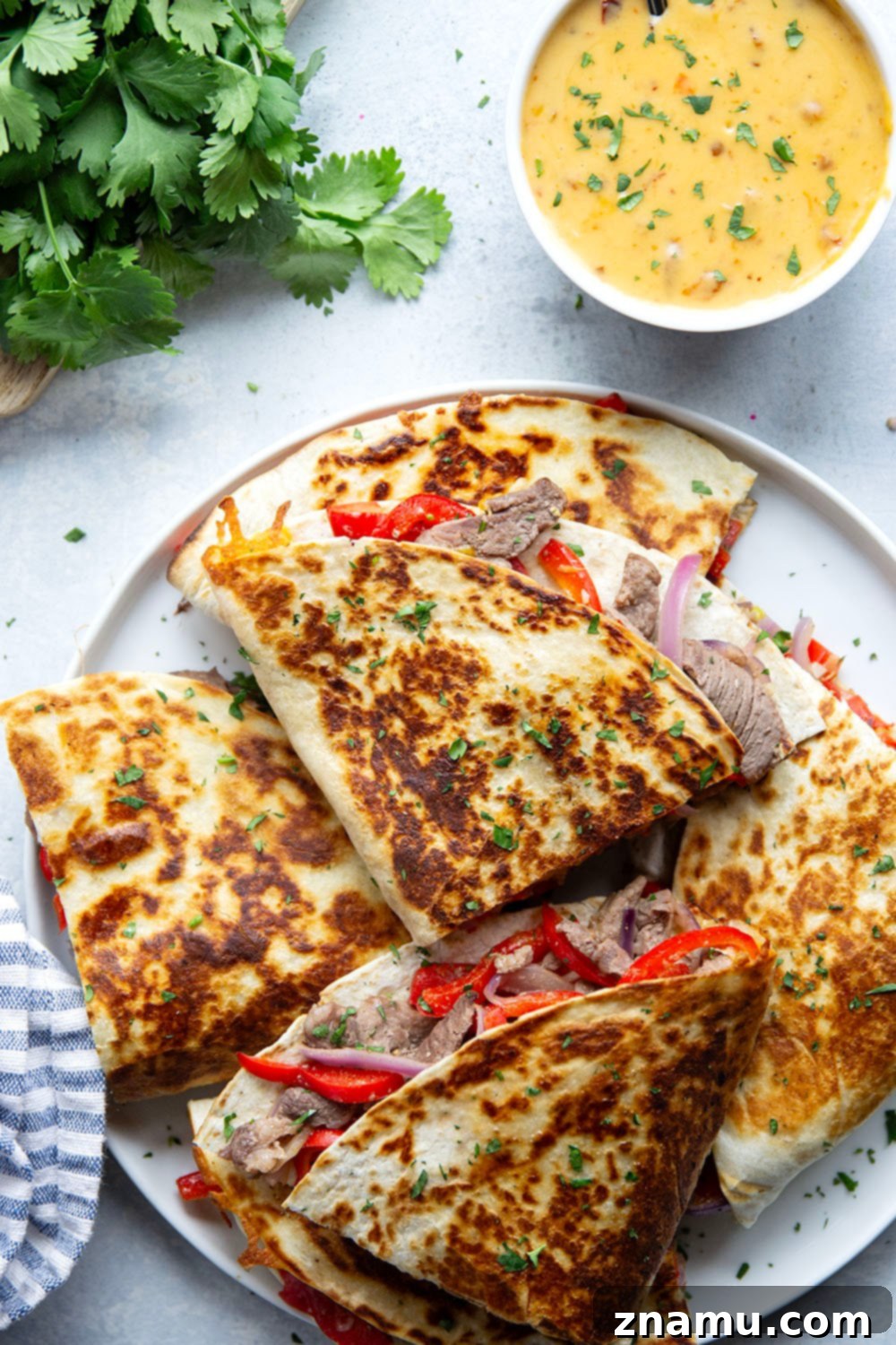 Spicy Chipotle Queso Steak Quesadillas 3 Golden-brown, cheesy steak quesadillas ready to be served with a side of chipotle queso.
