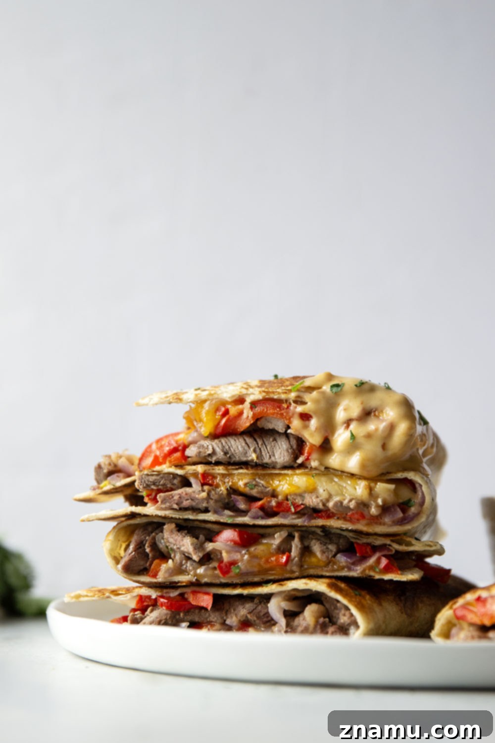 Spicy Chipotle Queso Steak Quesadillas 4 Close-up of a steak quesadilla half, revealing the tender steak, peppers, and melted cheese inside.