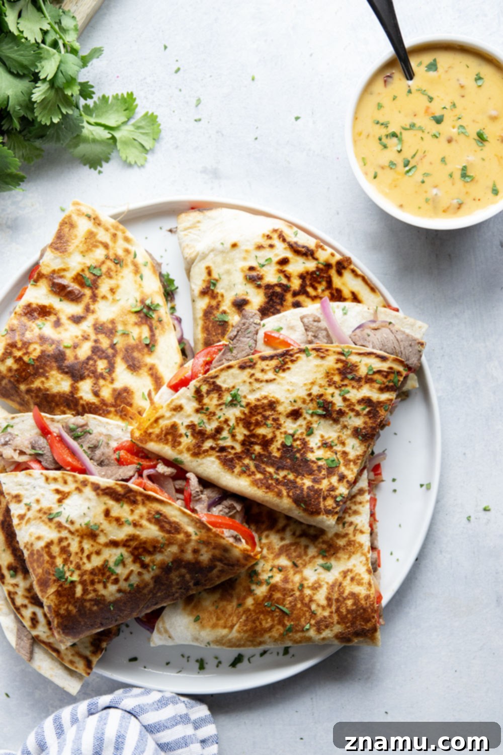 Spicy Chipotle Queso Steak Quesadillas 5 Various quesadilla ingredients including cooked steak, peppers, onions, and shredded cheese laid out on a cutting board.