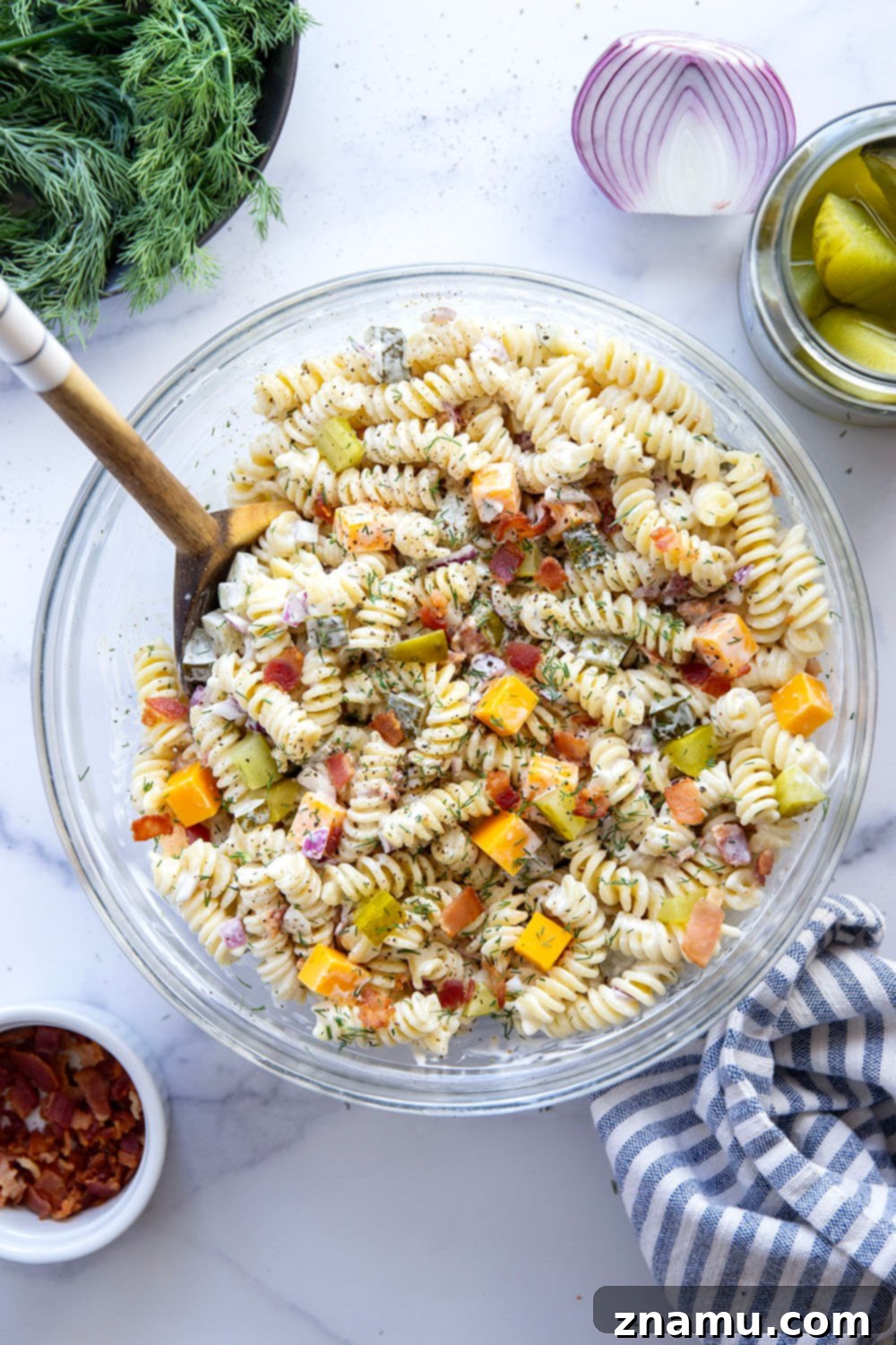 Zesty Bacon Dill Pasta Salad 3 Close-up of creamy dill pickle pasta salad, showing cooked pasta, bacon bits, cheddar cubes, and chopped pickles.