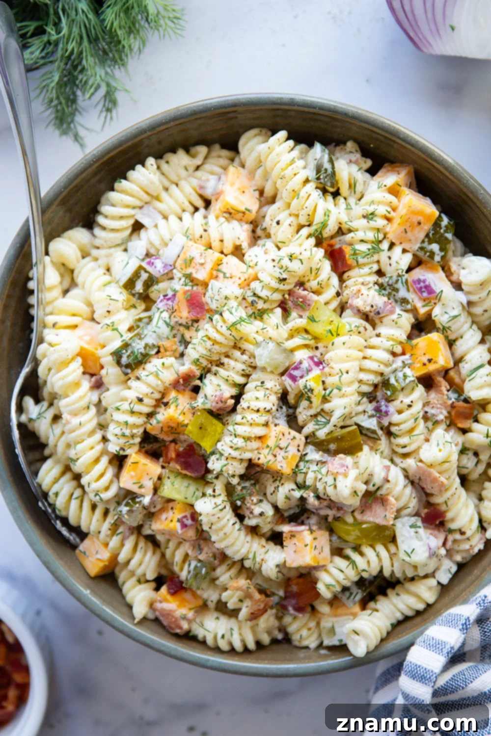 Zesty Bacon Dill Pasta Salad 4 A large bowl of creamy pasta salad featuring dill pickles, bacon, and cheddar, seen from above.