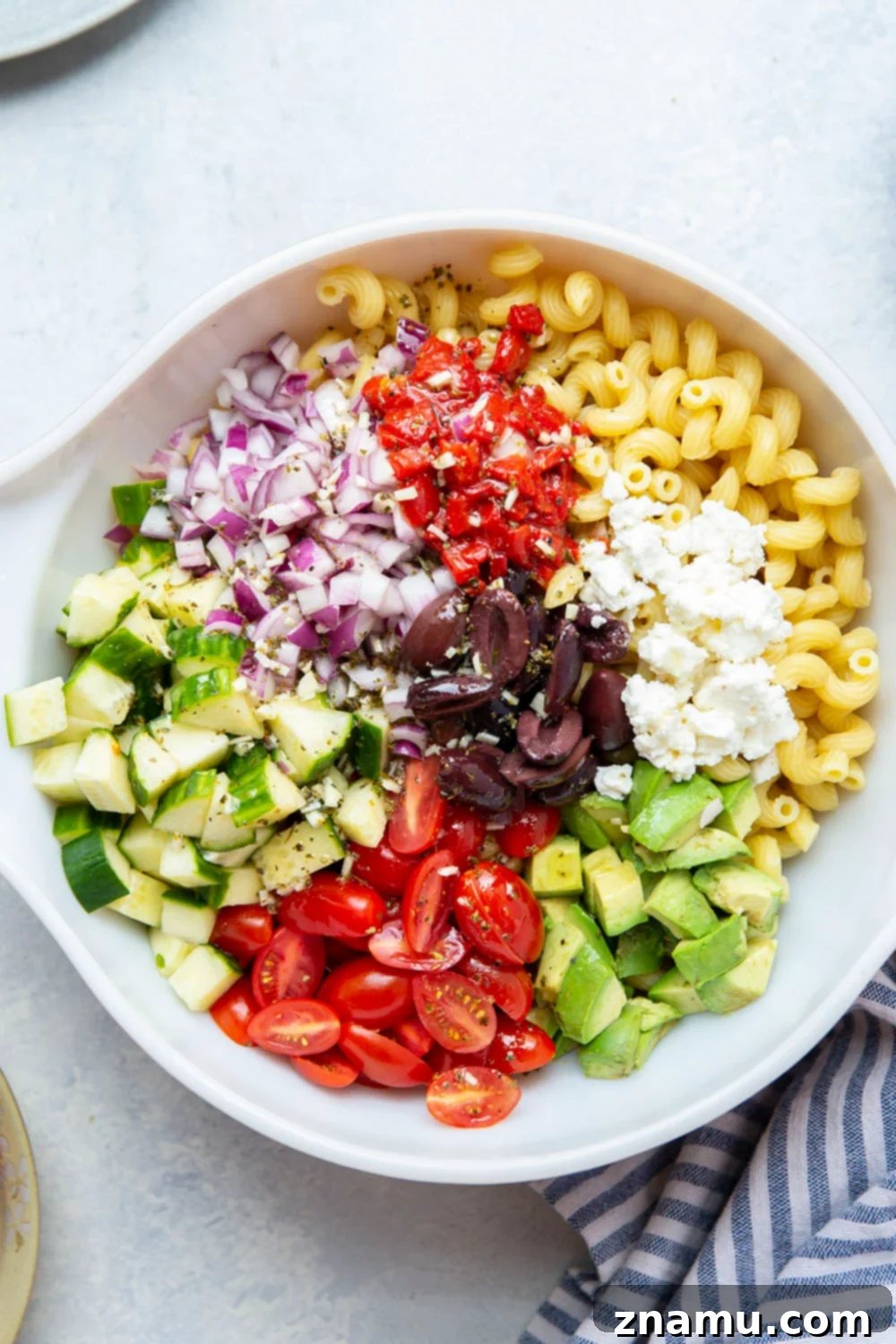 Mediterranean Sunshine Pasta 3 Close-up of Greek pasta salad, highlighting the colorful ingredients like tomatoes, cucumbers, feta, and olives.