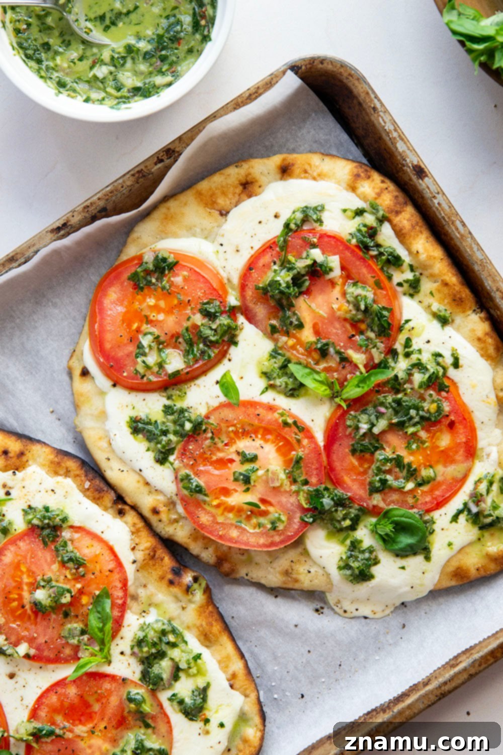 Fire-Kissed Caprese Flatbread with Aromatic Basil Chimichurri 4 Close-up of a grilled Caprese flatbread section, showing melted mozzarella and sliced tomatoes.