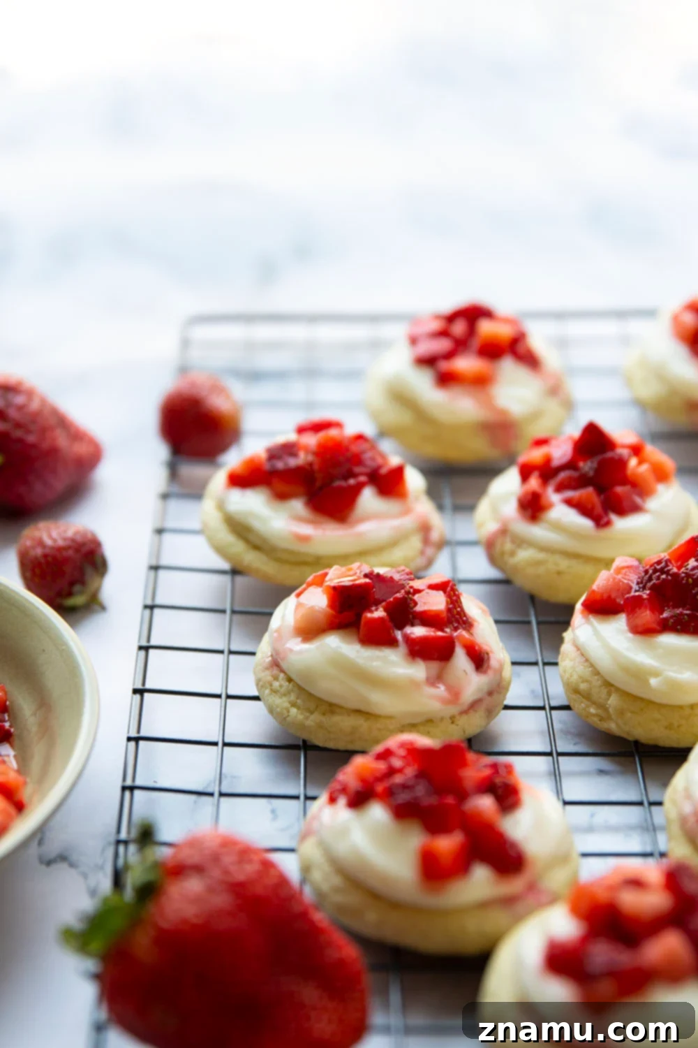 Ultimate Strawberry Shortcake Cookies 4 A close-up of the delicious layers of a Strawberry Shortcake Cookie: soft vanilla cookie, creamy frosting, and fresh diced strawberries.
