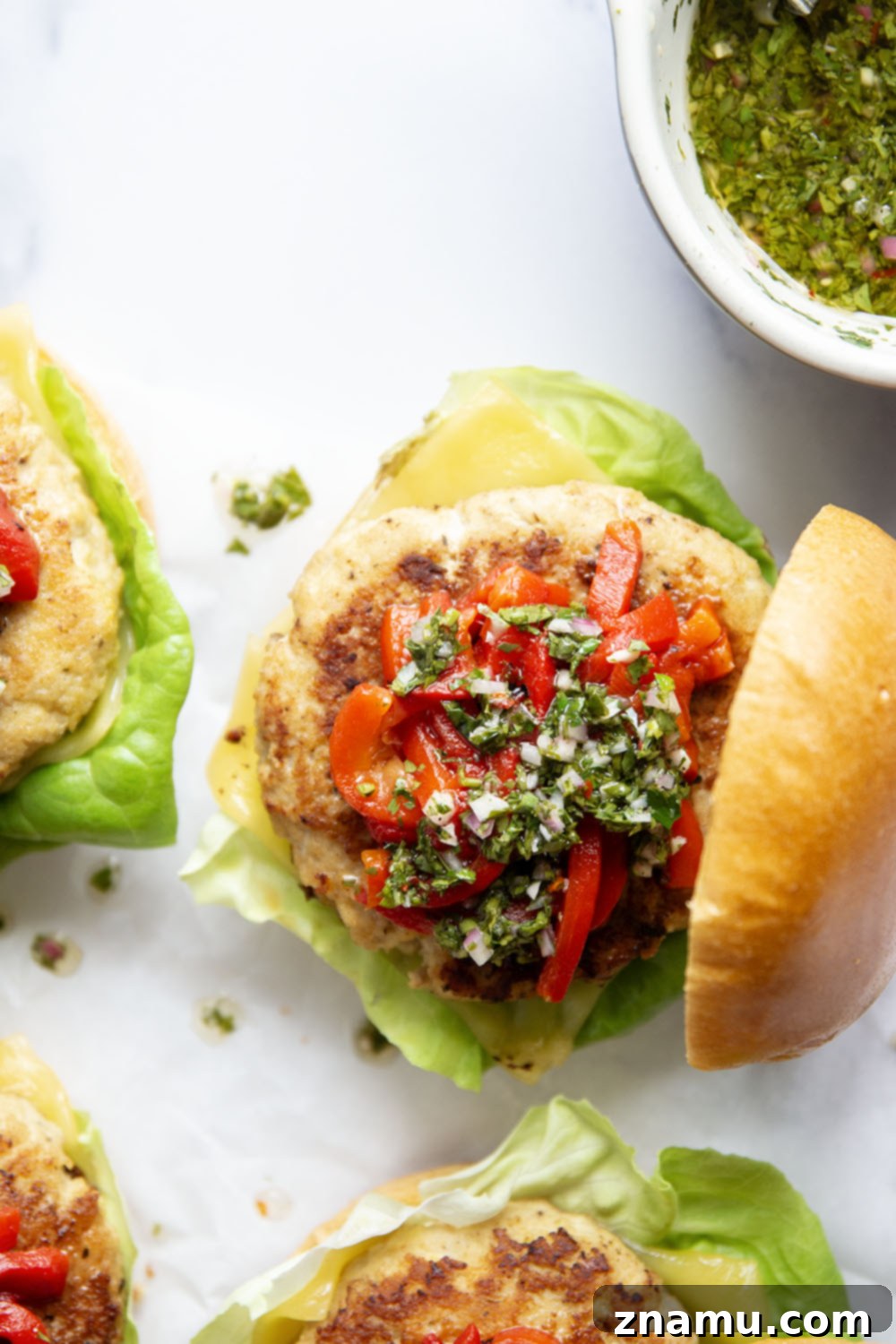 Zesty Chimichurri Turkey Burgers with Roasted Red Pepper and Cheddar 3 Close-up of a juicy Cheddar Turkey Burger patty on a bun with chimichurri and roasted red peppers