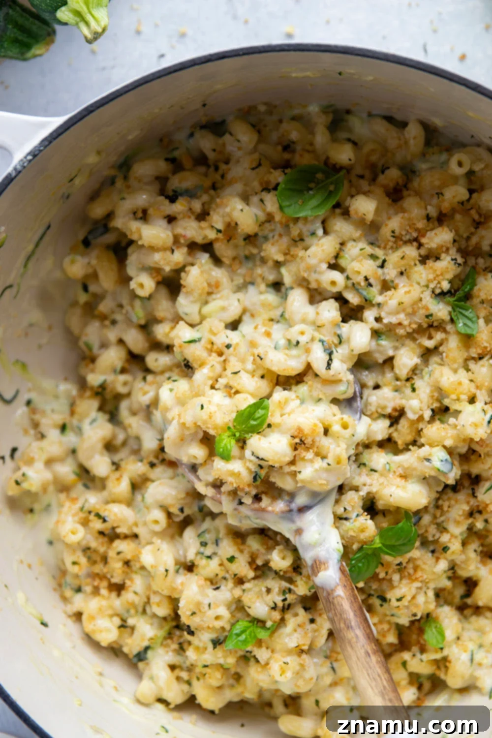 Creamy One-Pot Zucchini Mac and Cheese 5 Various uncooked pasta shapes on a wooden surface, suitable for mac and cheese.