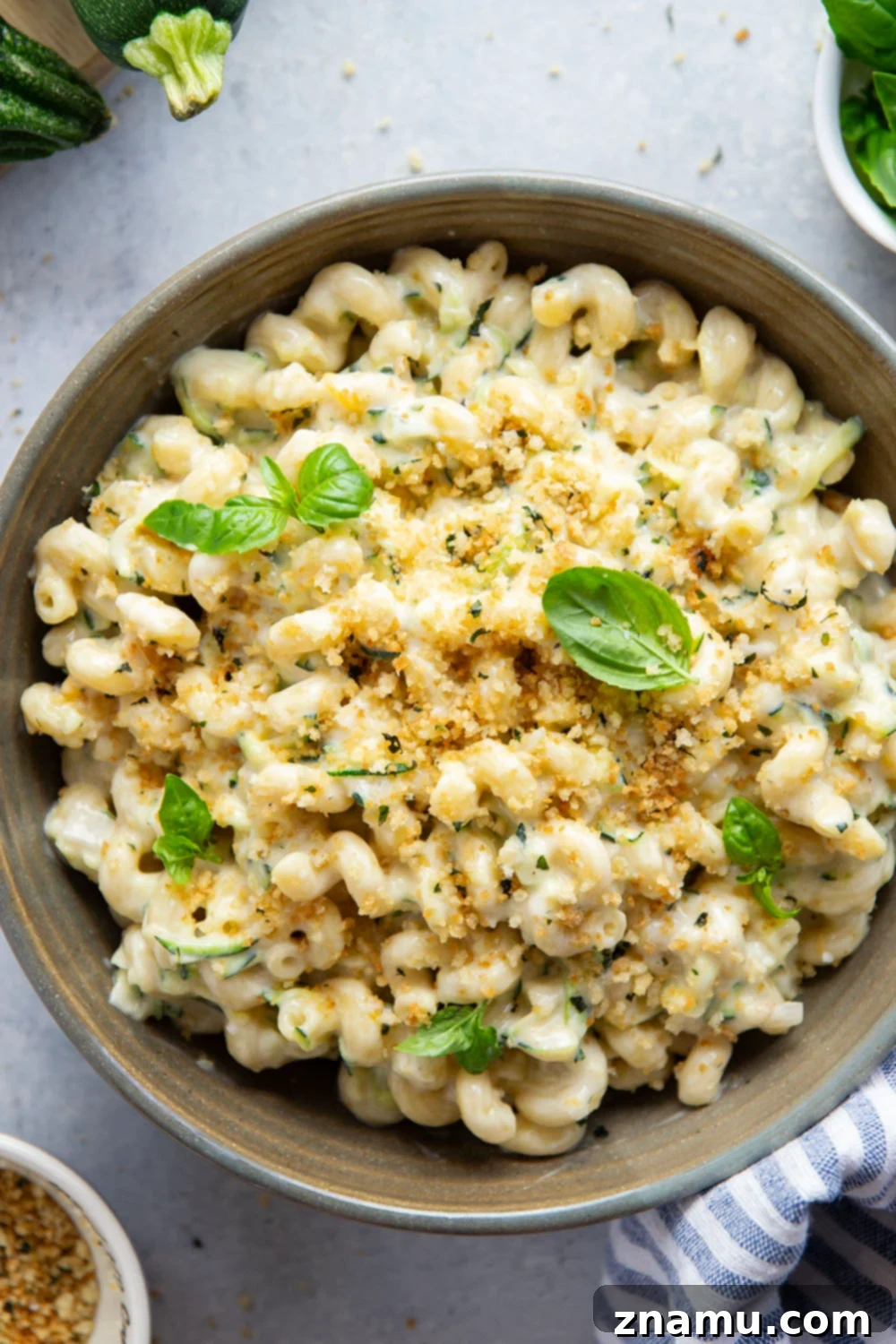 Creamy One-Pot Zucchini Mac and Cheese 6 A bowl of one-pot zucchini mac and cheese, garnished with fresh basil and breadcrumbs.
